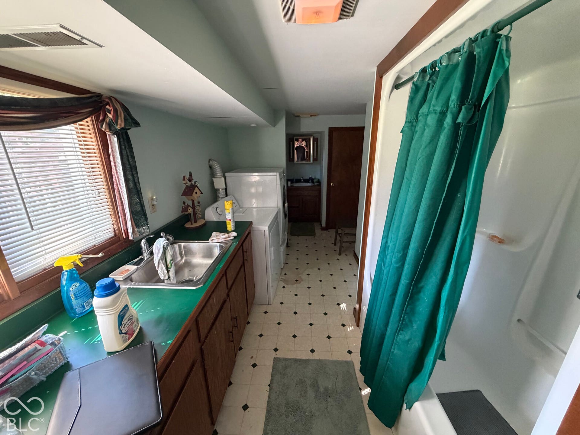 Utility room featuring a built-in sink, wood-finish cabinetry, and a window with blinds