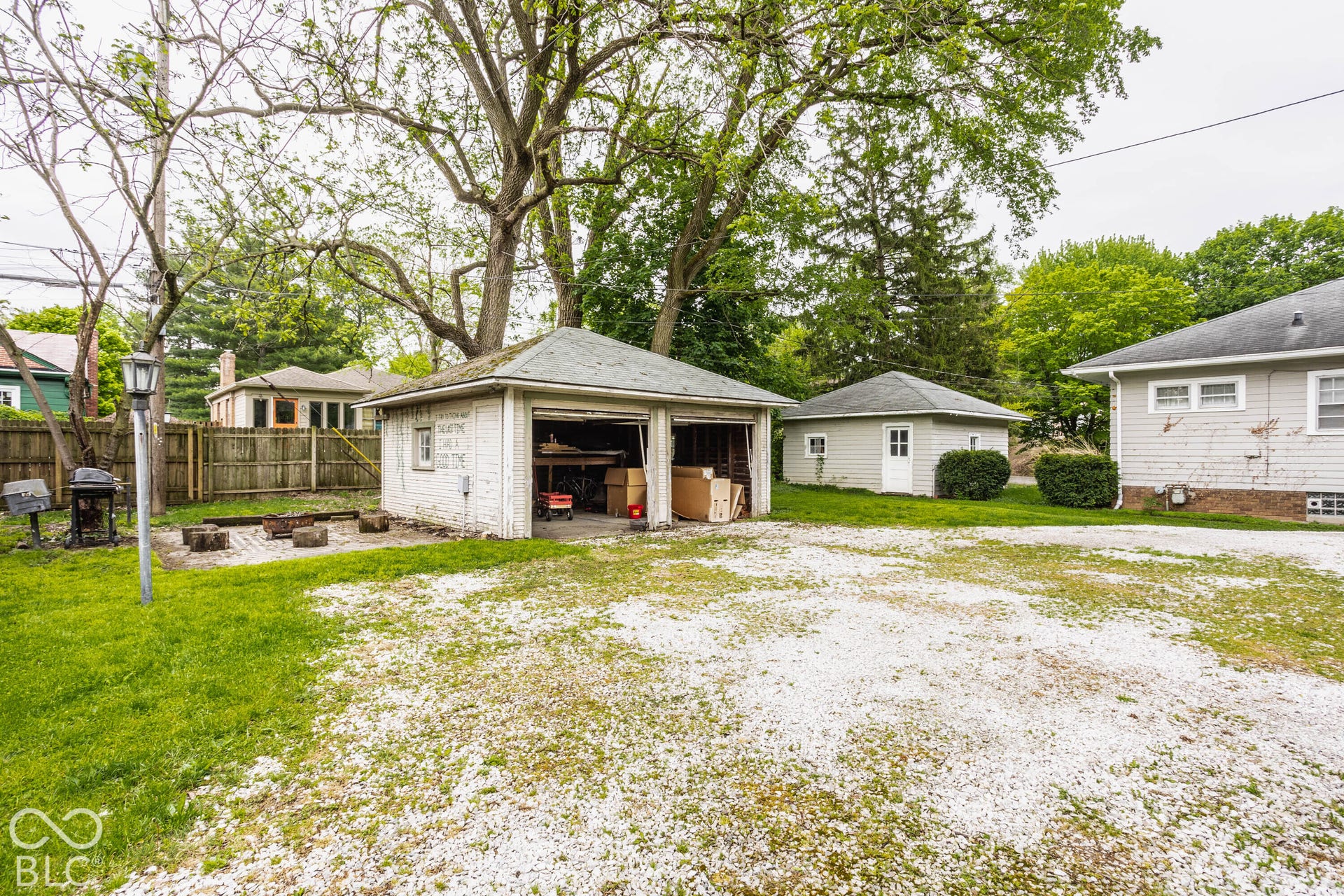 Detached two-car garage, gravel driveway, additional detached outbuilding, and a stone-paved patio area