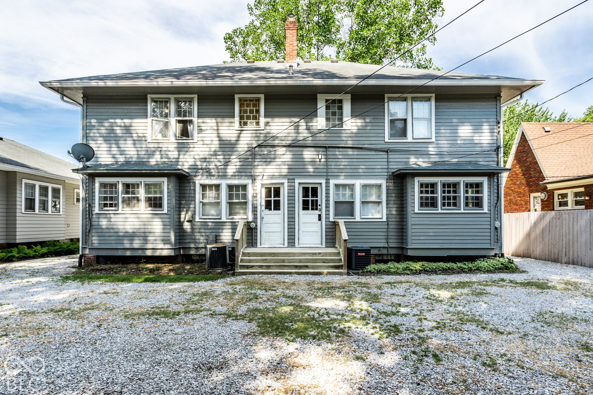 Two-story exterior with horizontal siding, multiple windows, and two separate entry doors