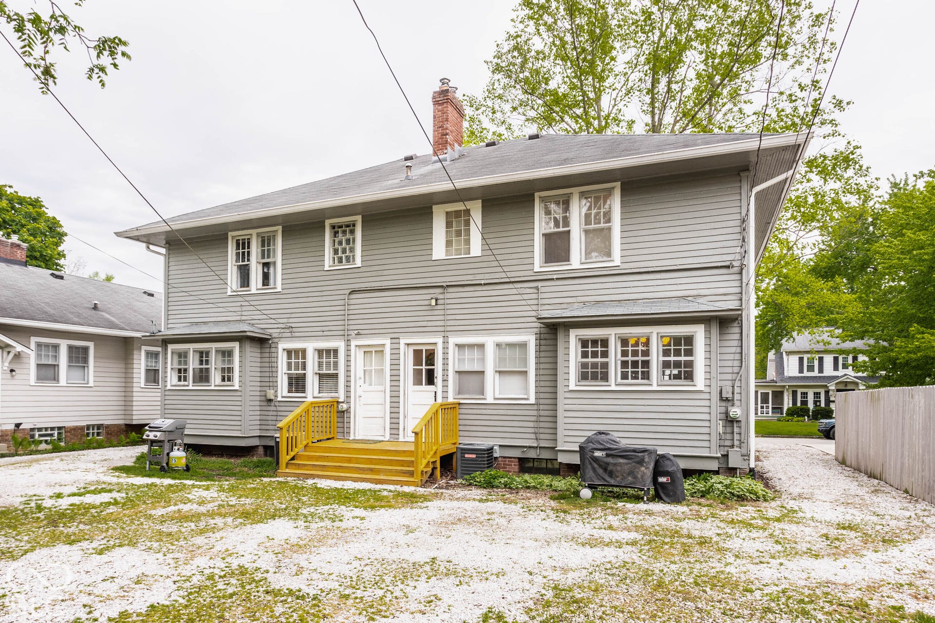 Two-story siding exterior with multiple windows, two exterior doors, and a wooden deck