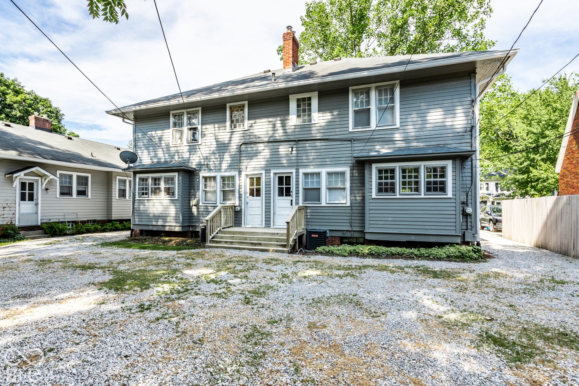 Light gray siding with a white trim, featuring multiple pane windows and two distinct entry doors