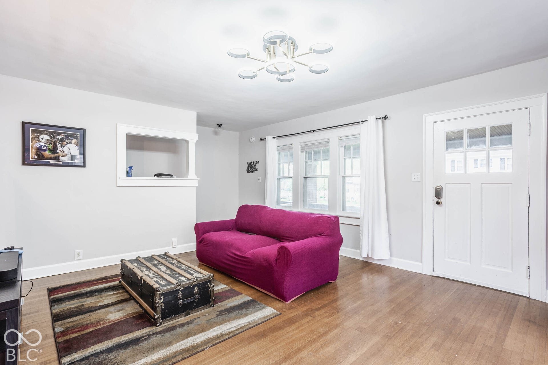 Hardwood flooring, painted interior walls, multi-pane windows, white trim, and a contemporary ceiling light fixture