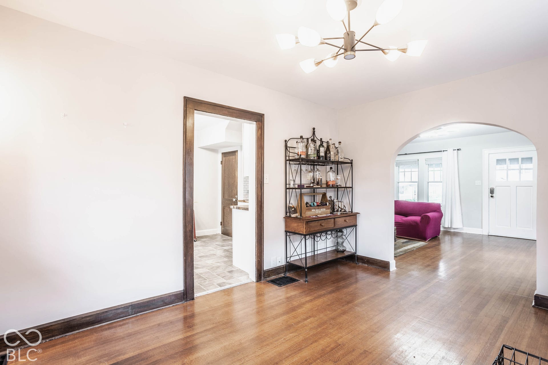 Hardwood flooring throughout, contemporary ceiling fixture, arched doorway, and solid wood trim