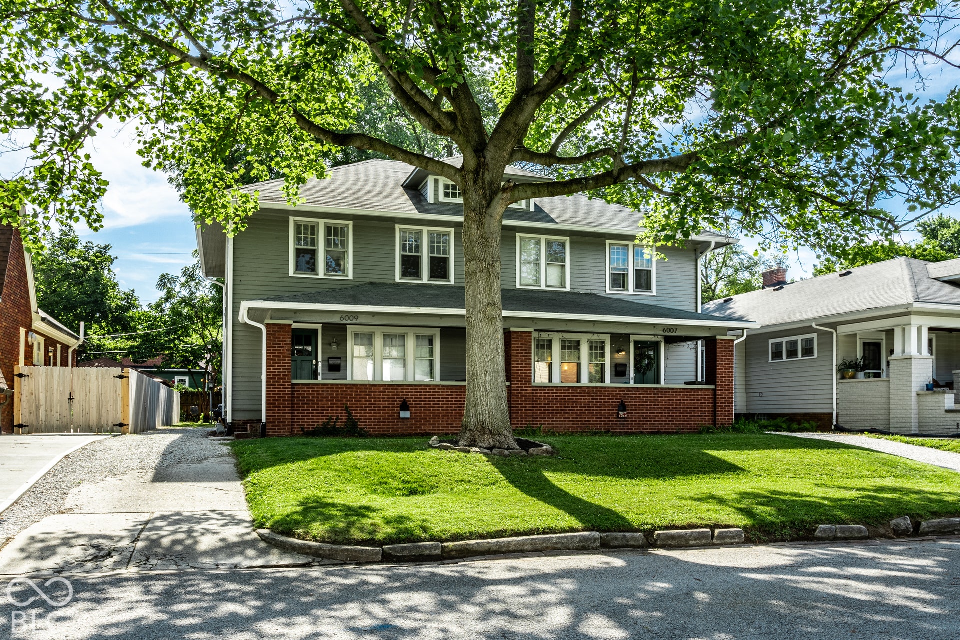 Two-story residence featuring a shingle roof, green siding, and a brick foundation