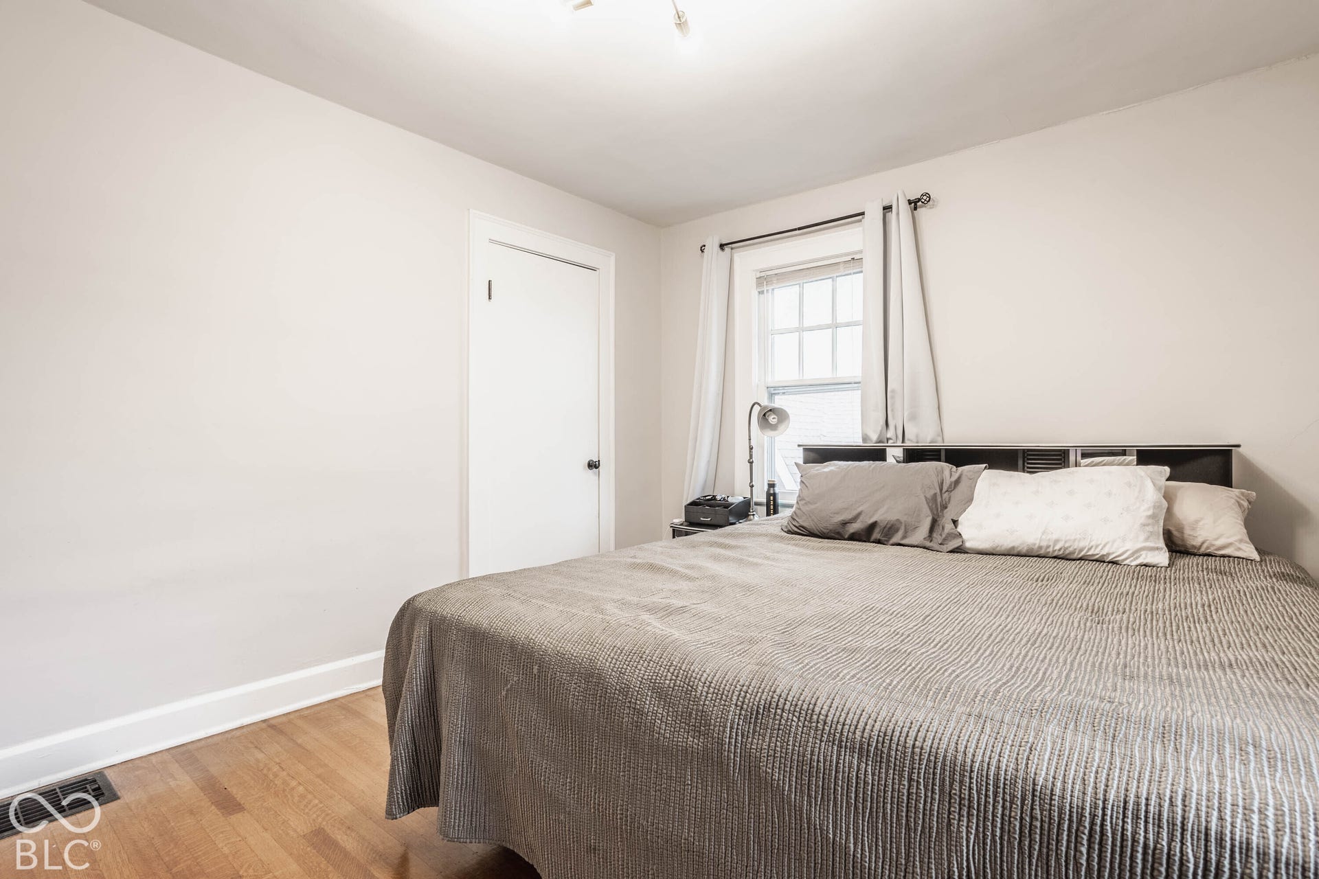 Wood-finish flooring, white trim, and a multi-pane window