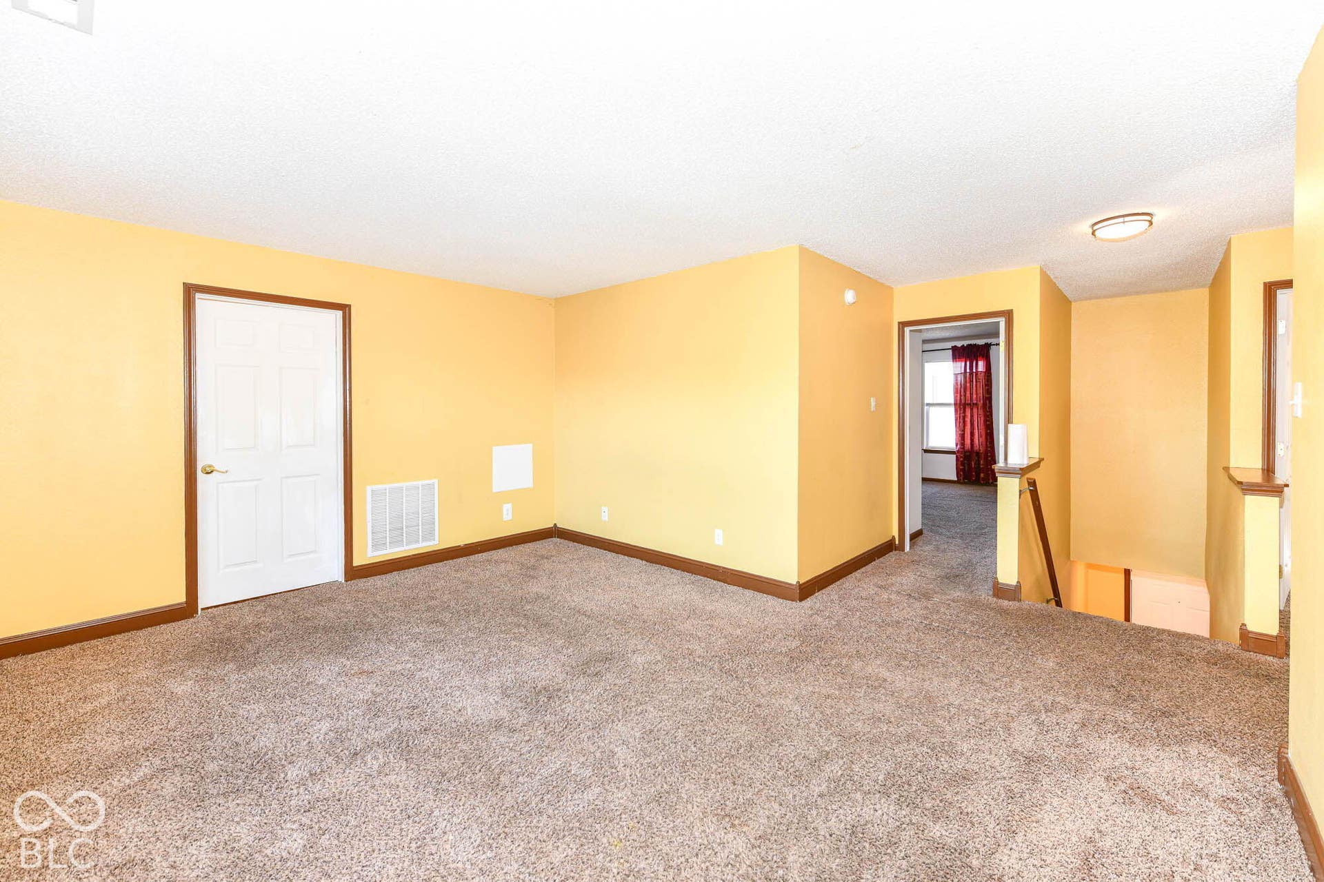 Carpeted flooring, white paneled door, wood-finish trim, and a flush mount ceiling light fixture