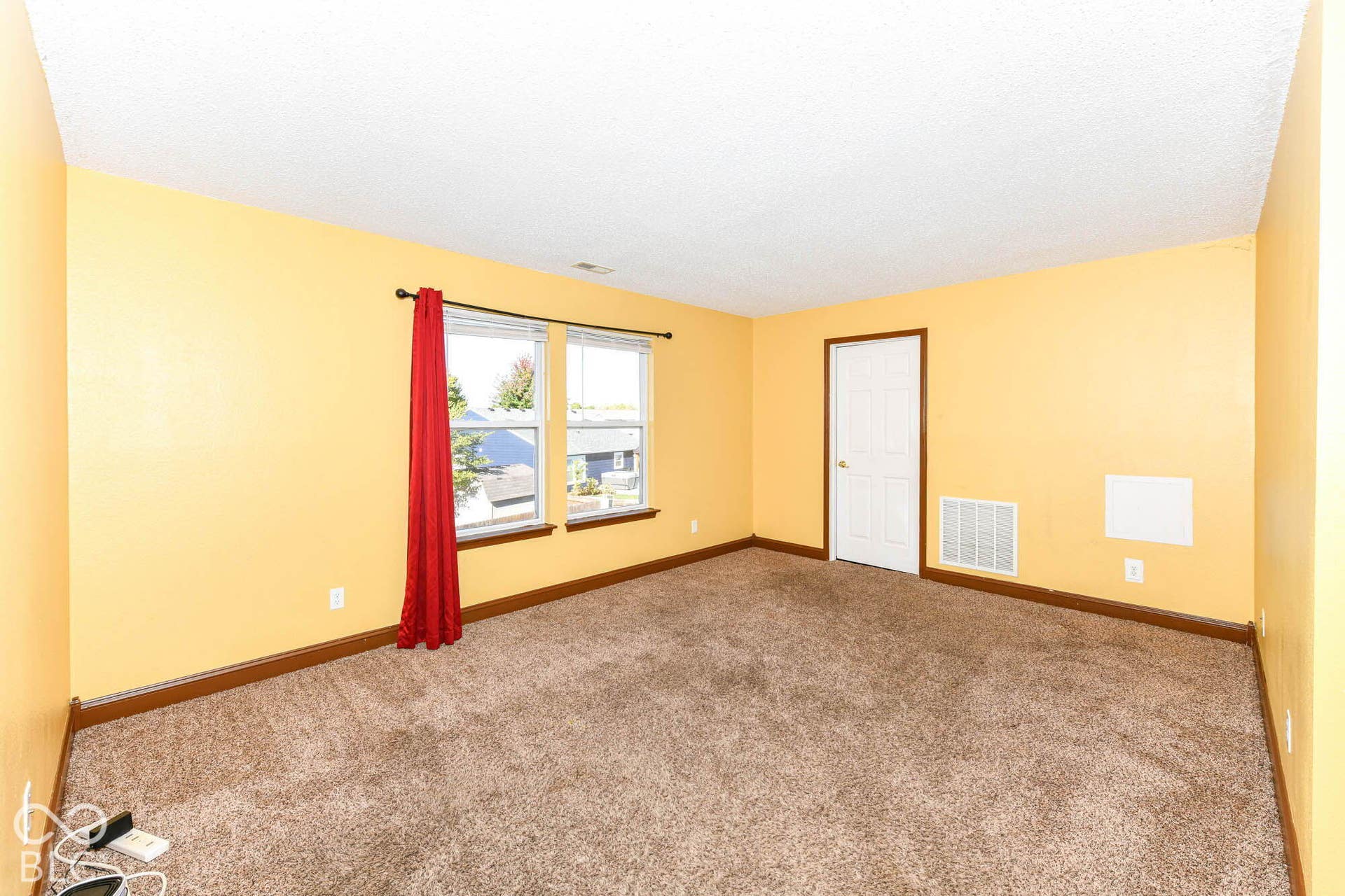 Textured carpeting, yellow painted walls, two windows, and a white interior door