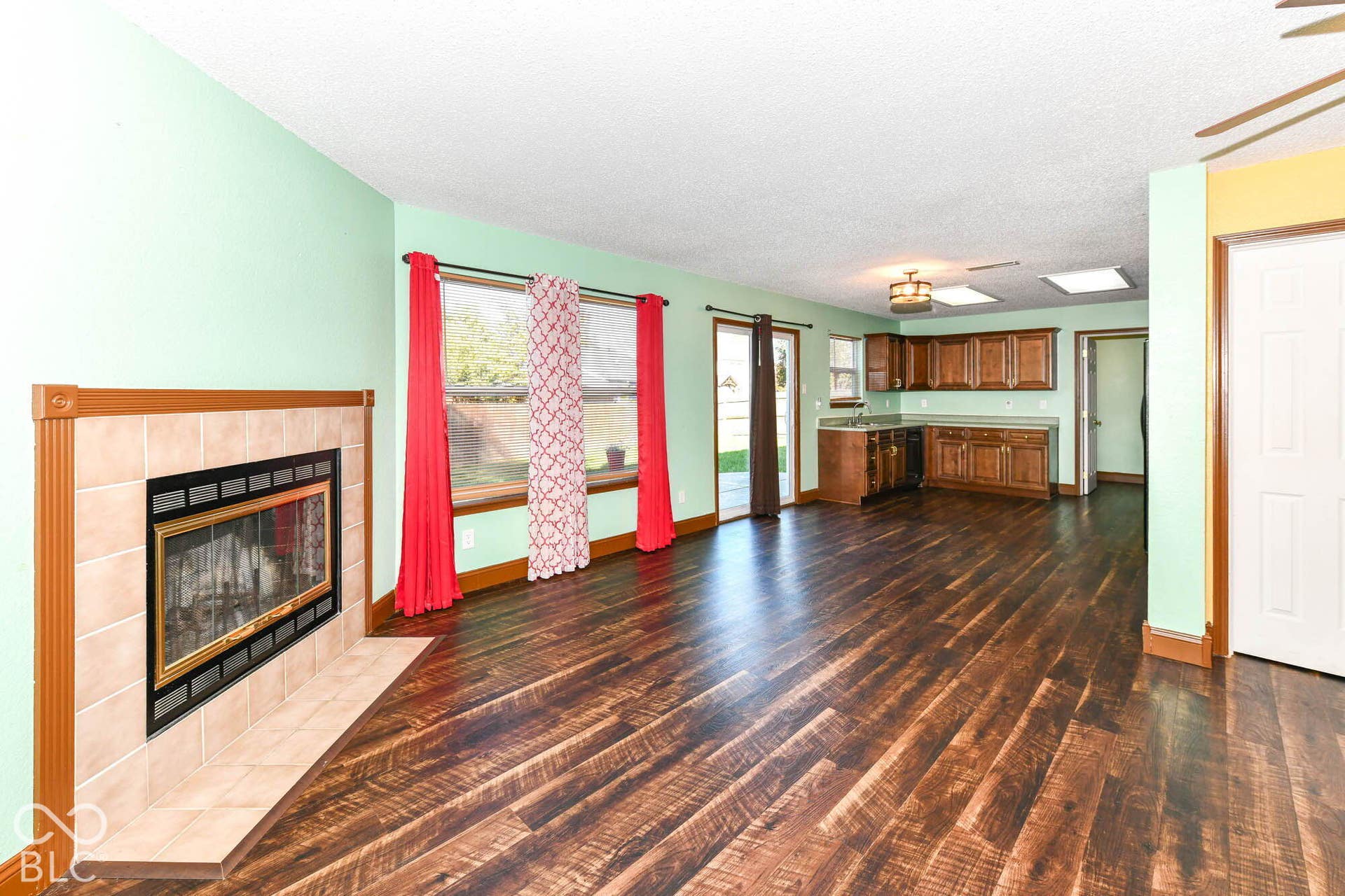Wood-finish flooring throughout, tile-surround fireplace, and wood cabinetry with dark countertops
