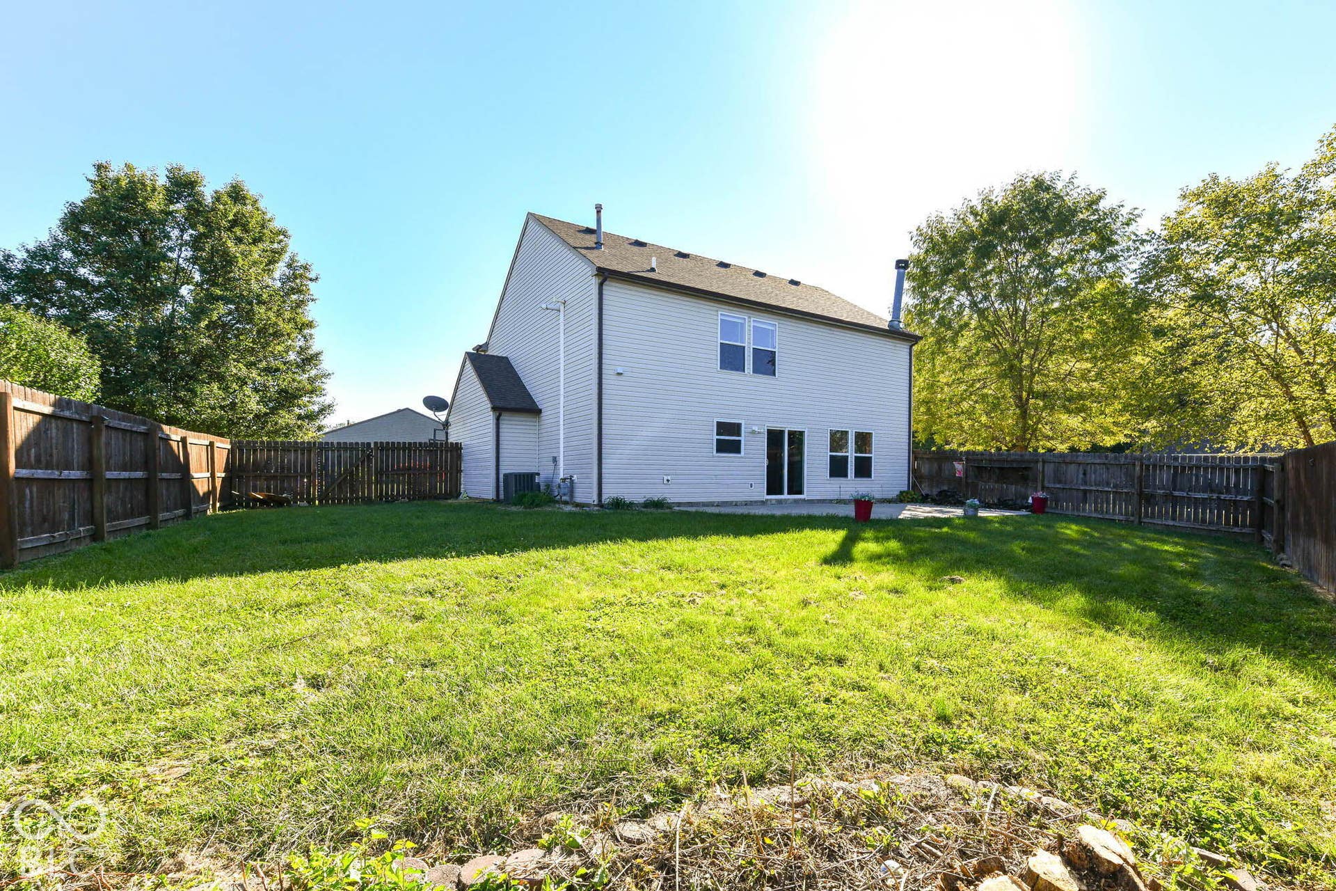 Expansive backyard with a manicured lawn, full privacy fencing, and a concrete patio