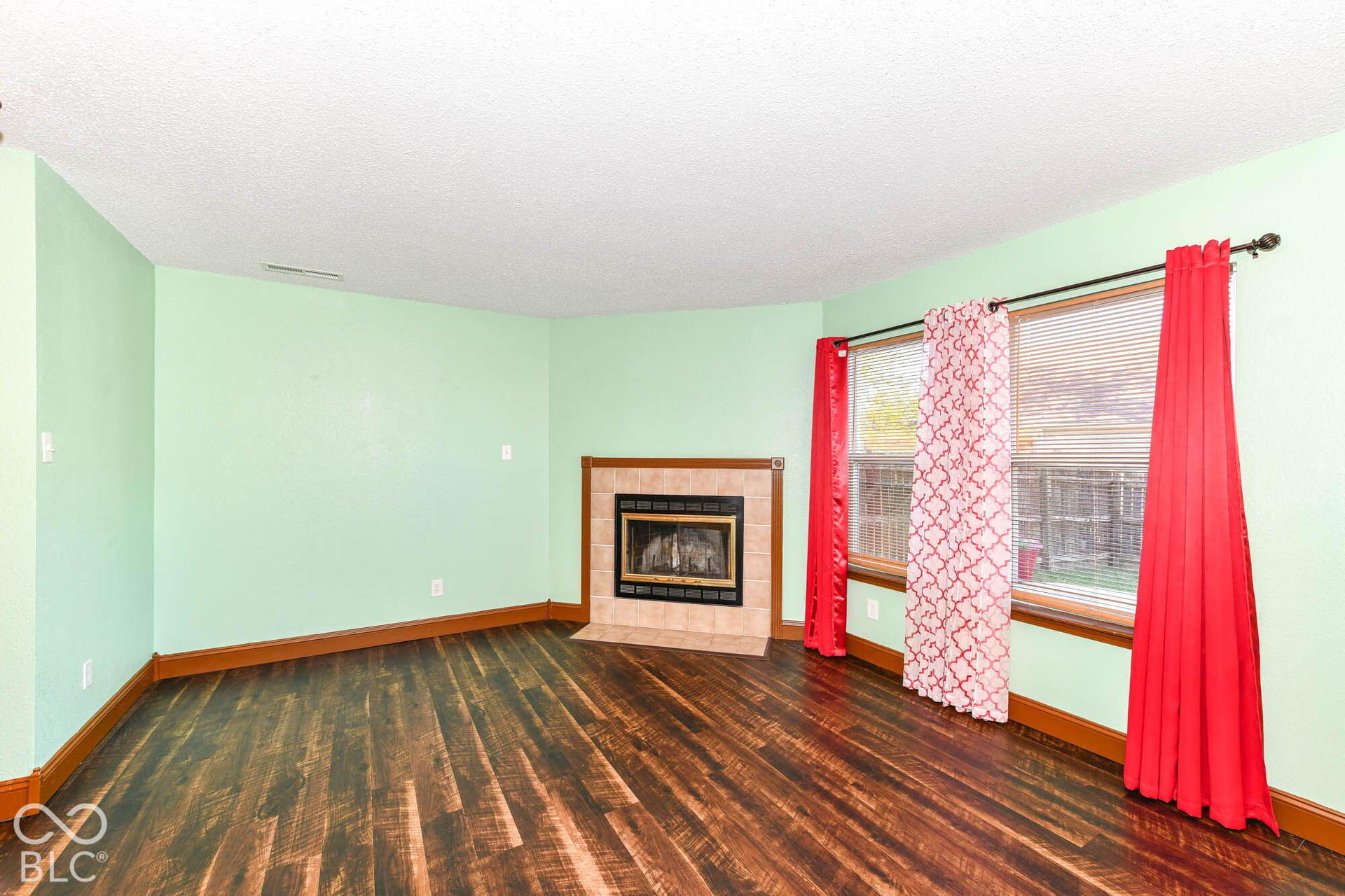 Wood-finish flooring, tiled fireplace surround, and multiple windows providing natural light