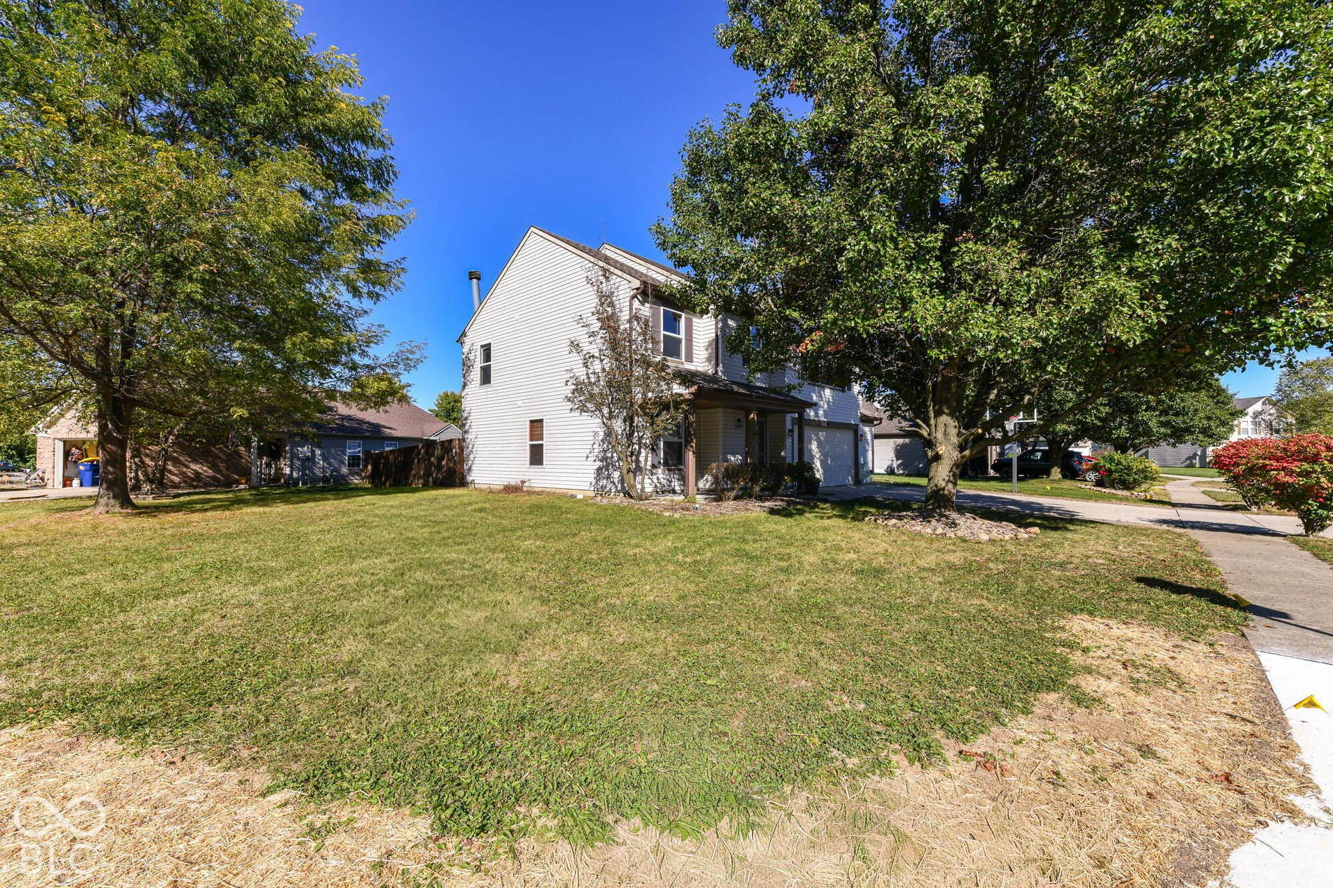Two-story residence with white siding, a prominent front porch, and a side-facing garage
