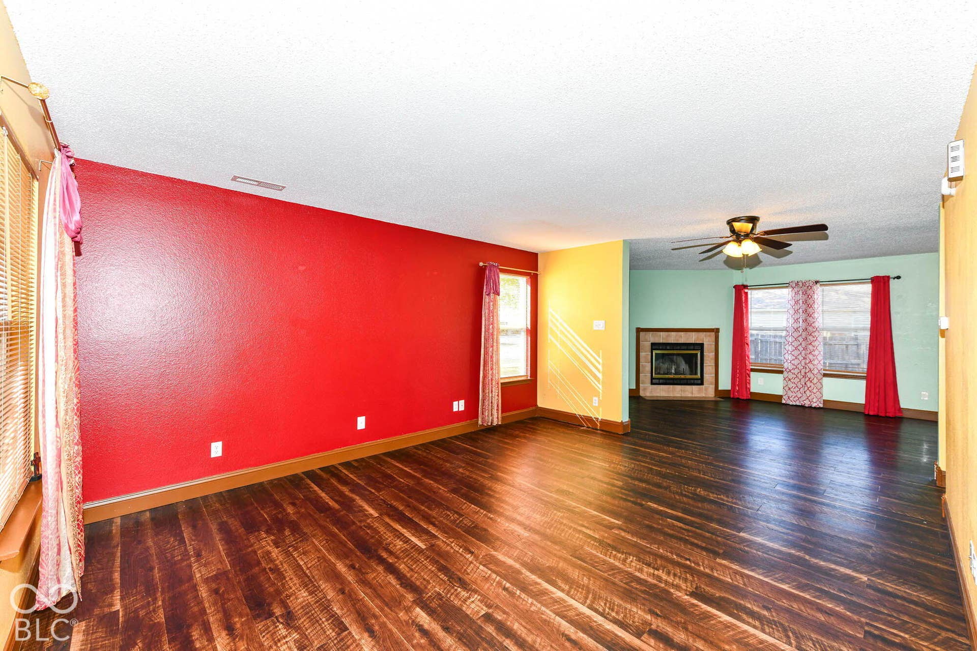 Wood-finish flooring throughout, featuring a corner fireplace with a tile surround, and a ceiling fan
