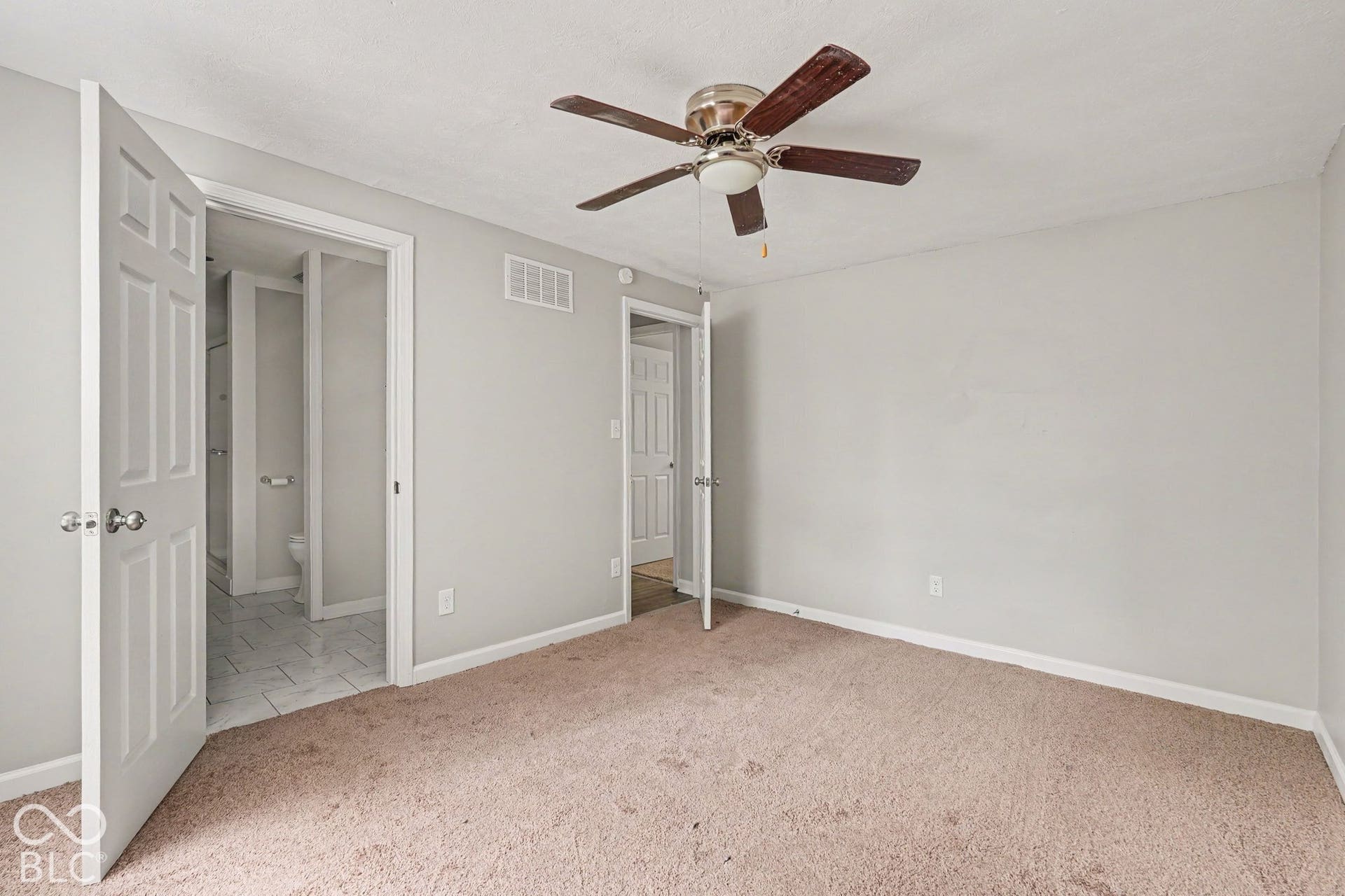 Carpeted room with a ceiling fan light fixture and neutral wall color