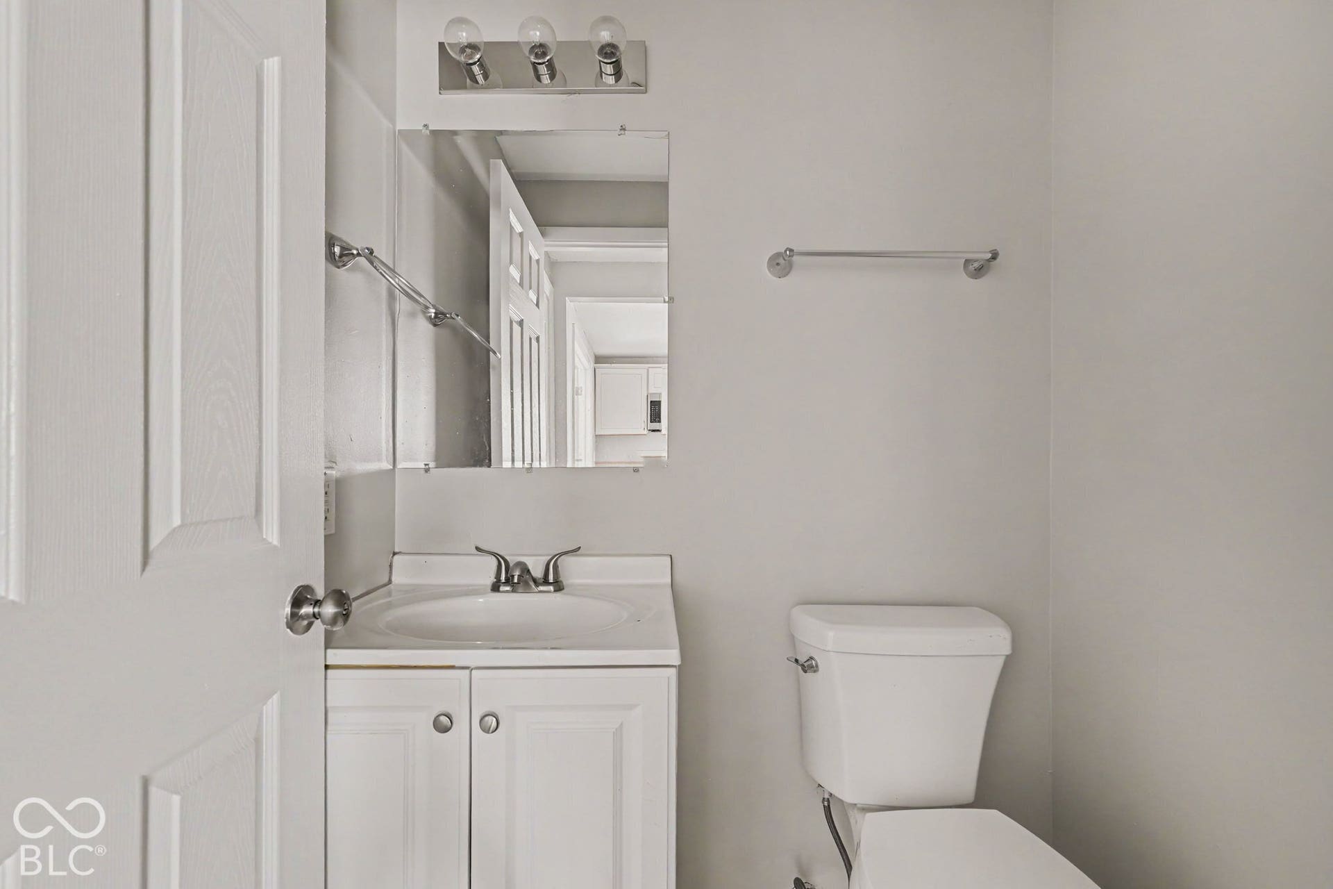 White vanity with a laminate countertop, undermount sink, and chrome faucet