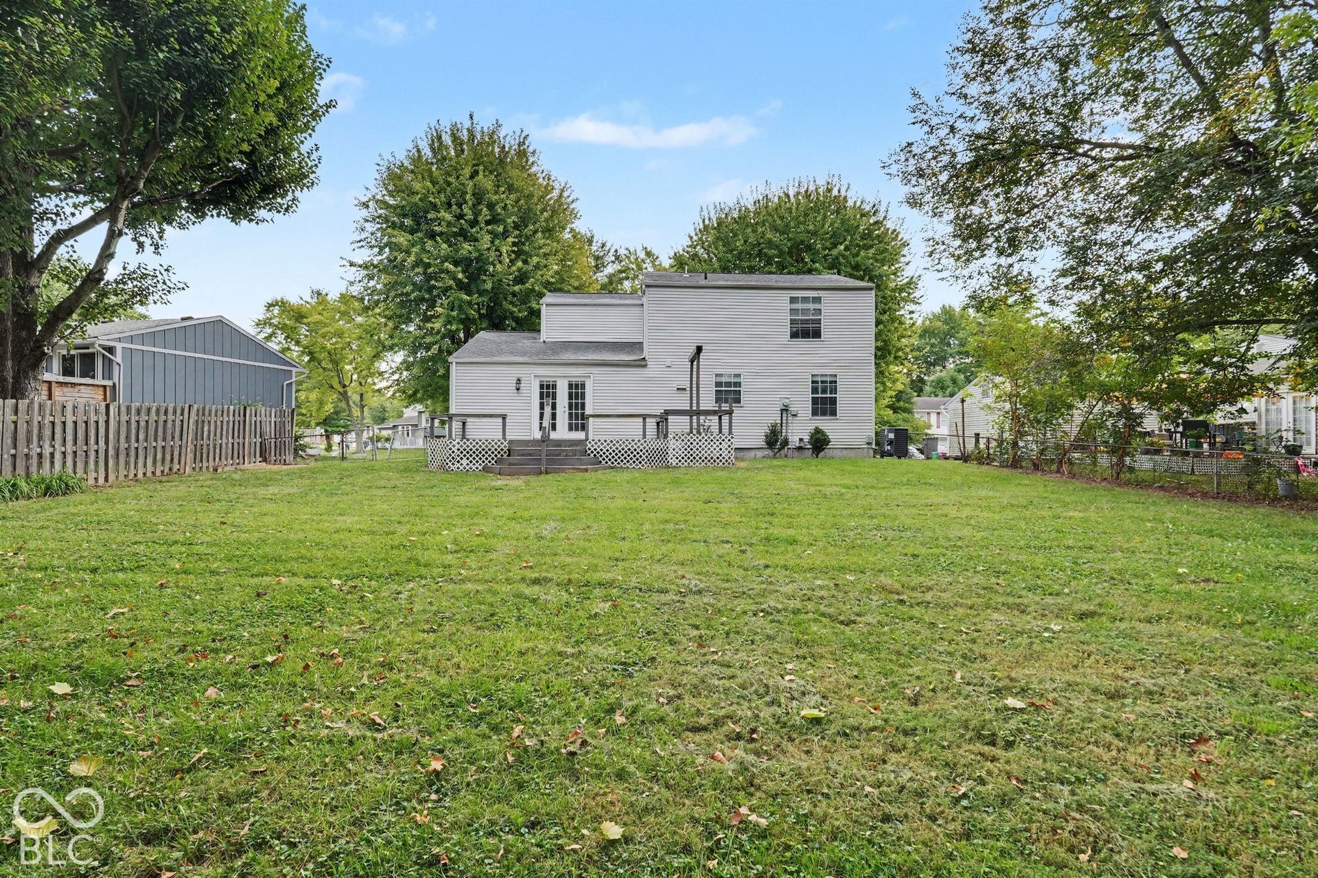 Expansive grass lawn with mature trees and a wood picket fence