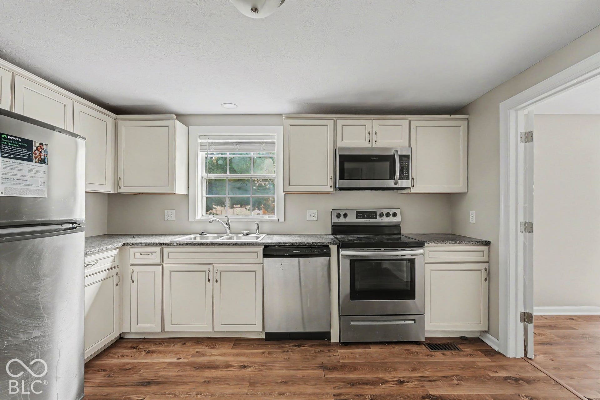 Modern kitchen featuring wood-finish flooring, white cabinetry, and stainless steel appliances
