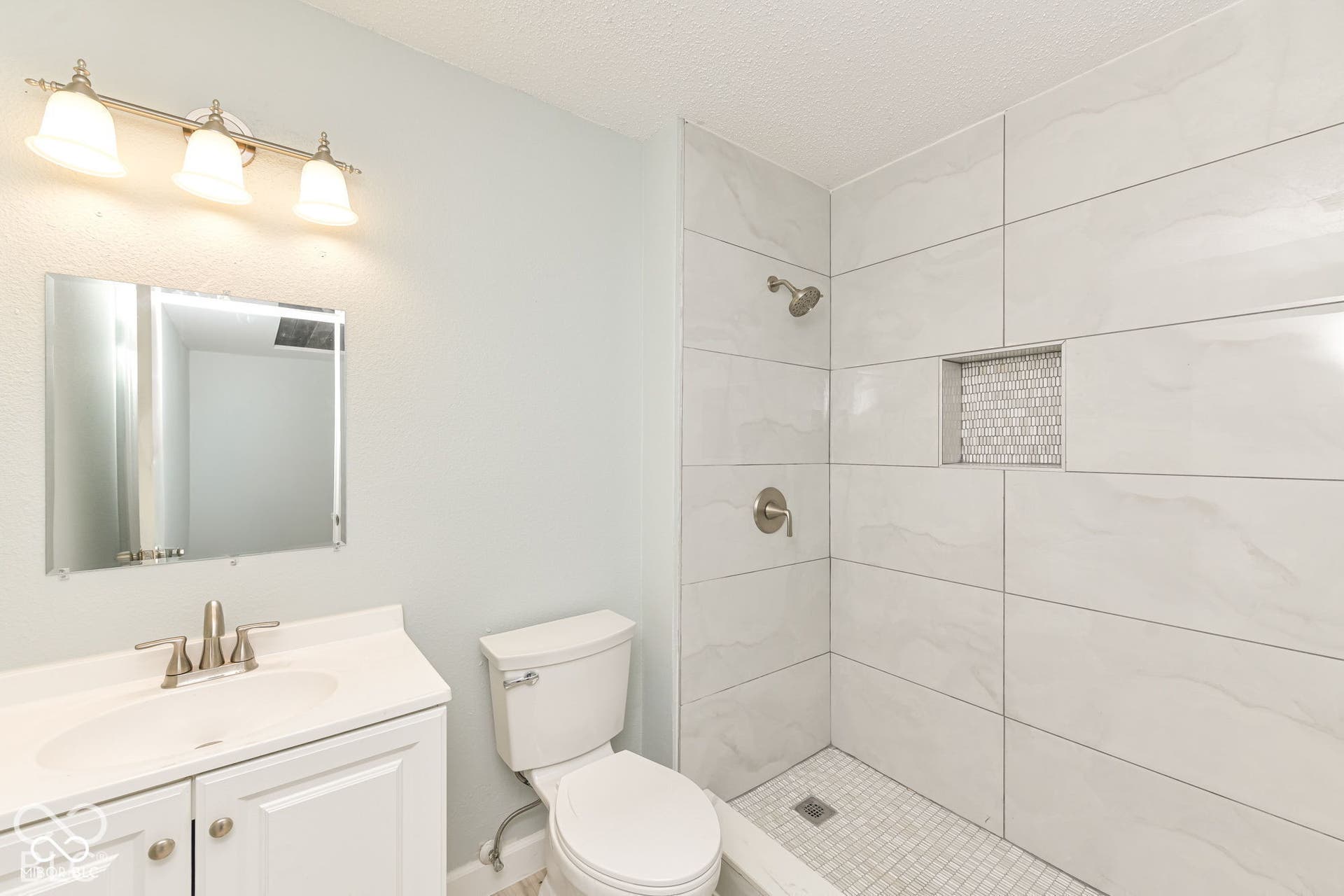 White vanity with an integrated sink, brushed nickel faucet, and overhead vanity lighting