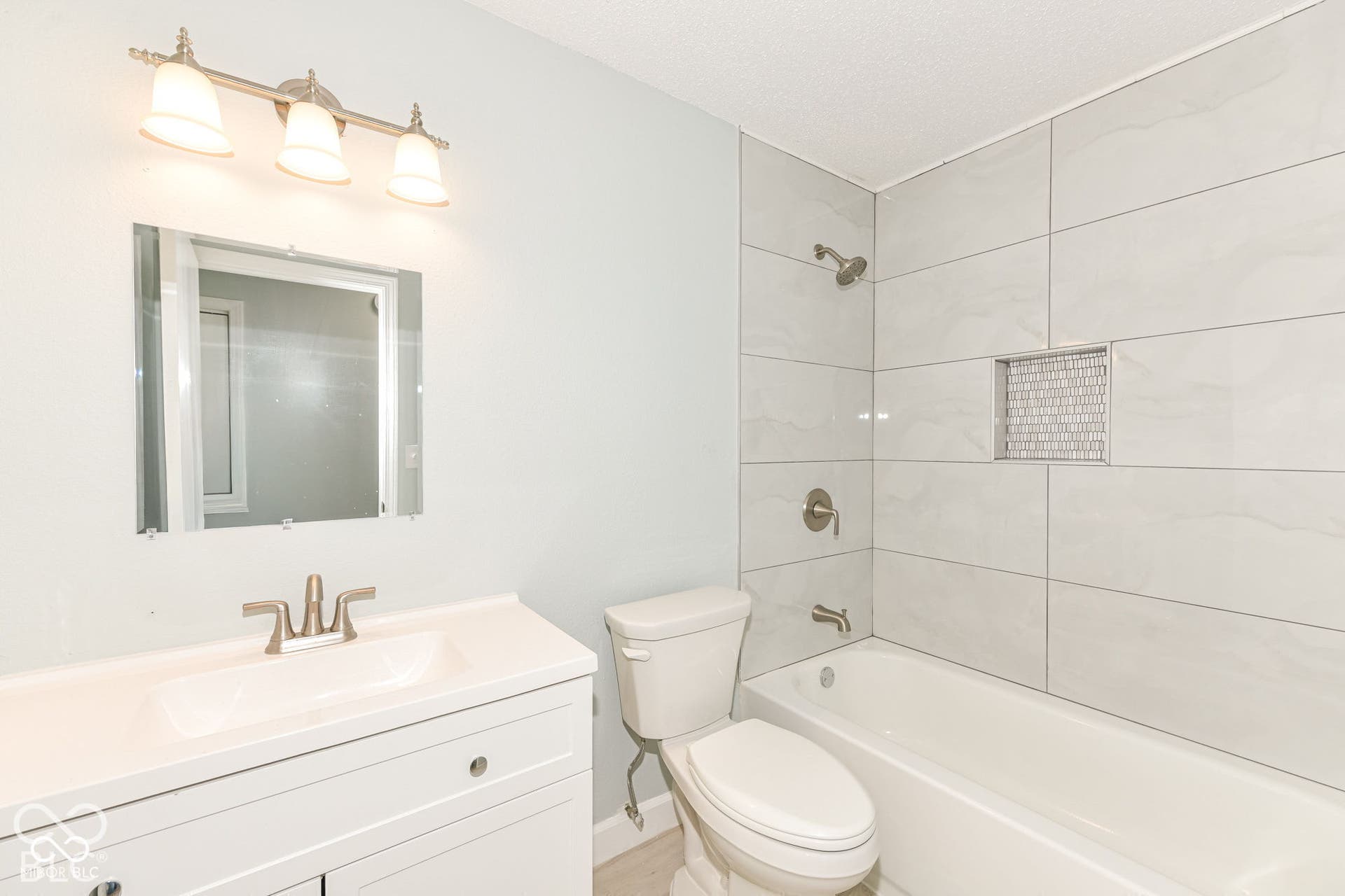 White vanity with integrated sink, brushed nickel faucet, and overhead three-light fixture