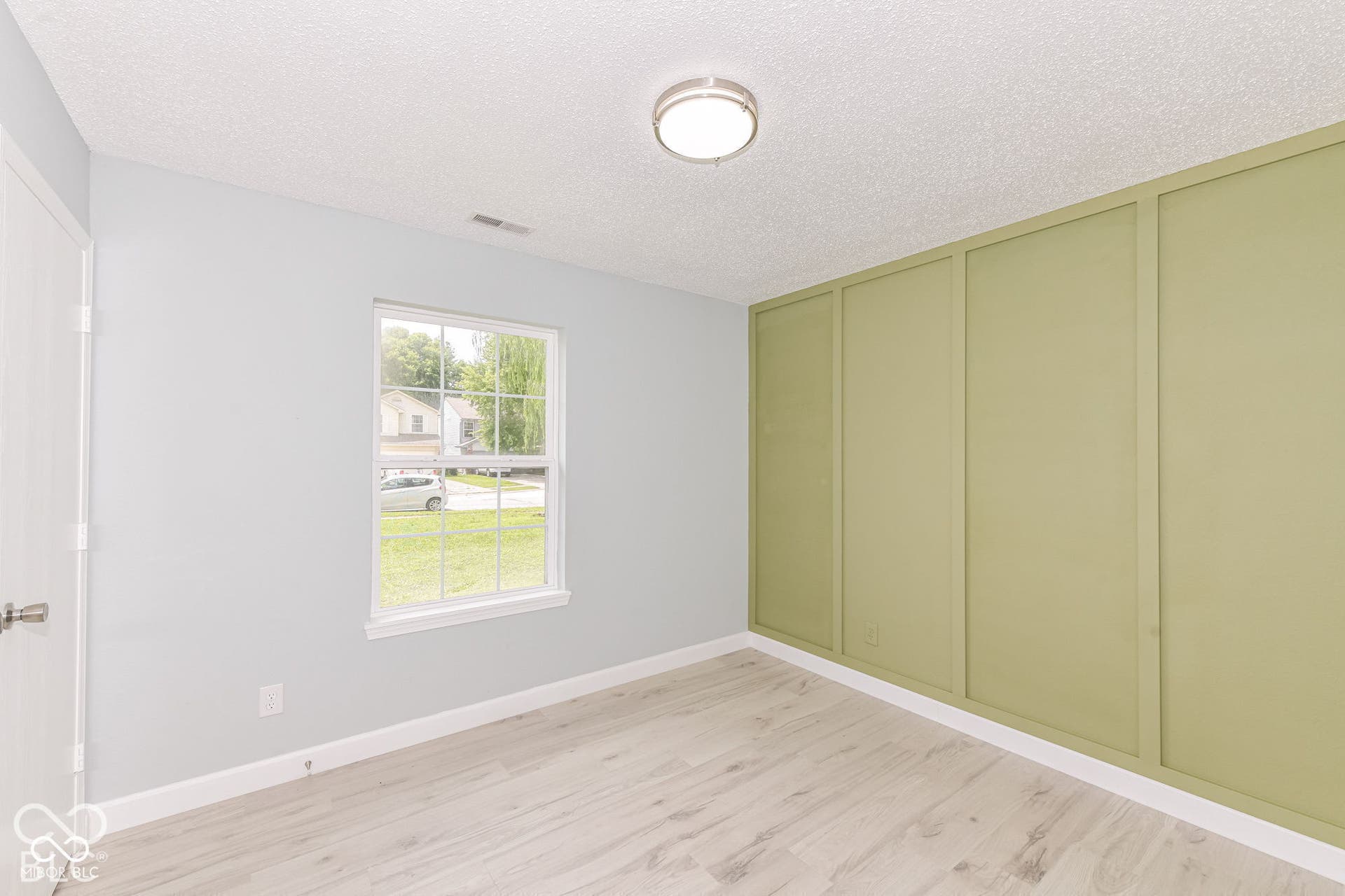 Light wood-finish flooring, a contemporary flush-mount ceiling light, and a window with white trim