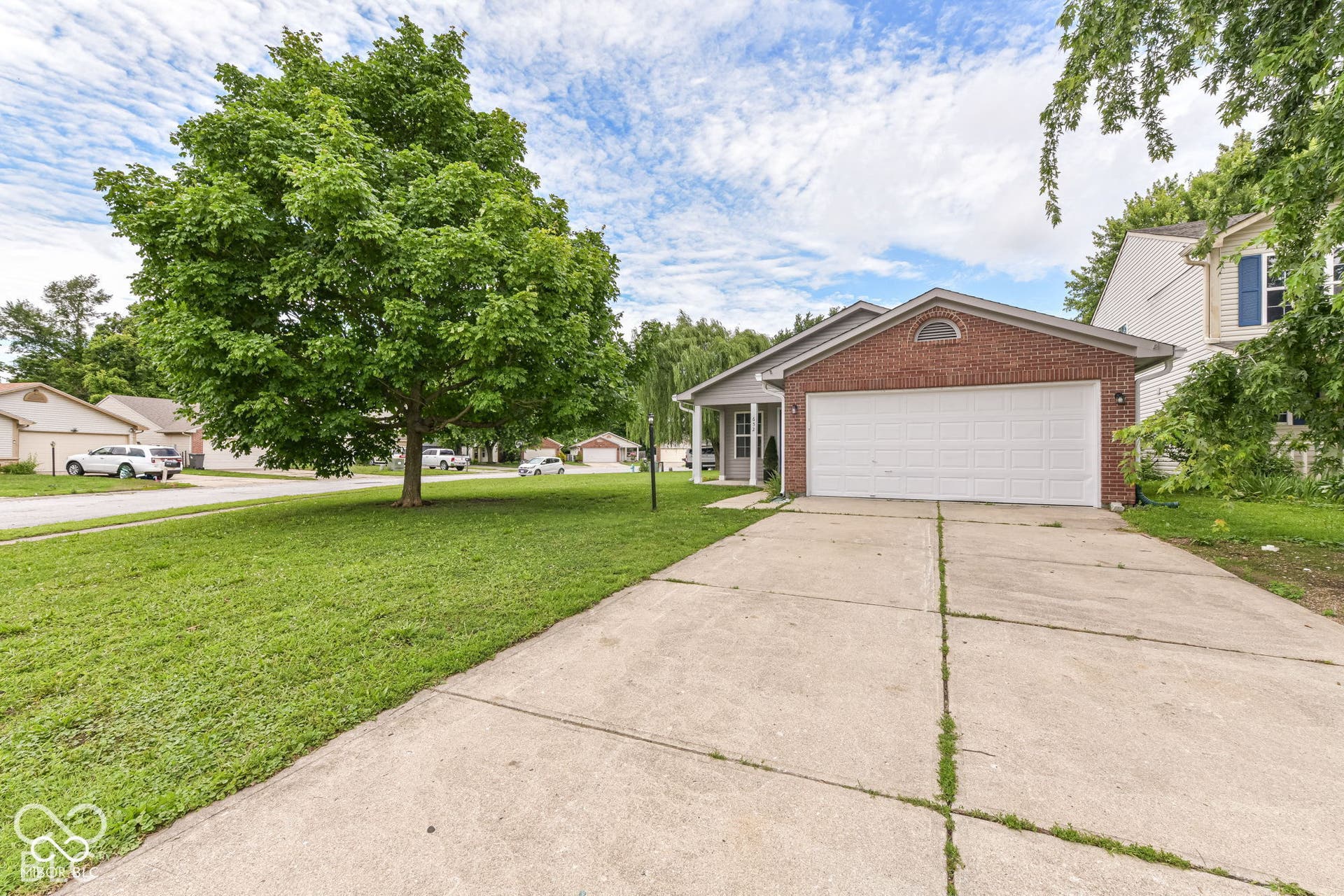 Brick facade with an arched window accent, attached garage, and a concrete driveway