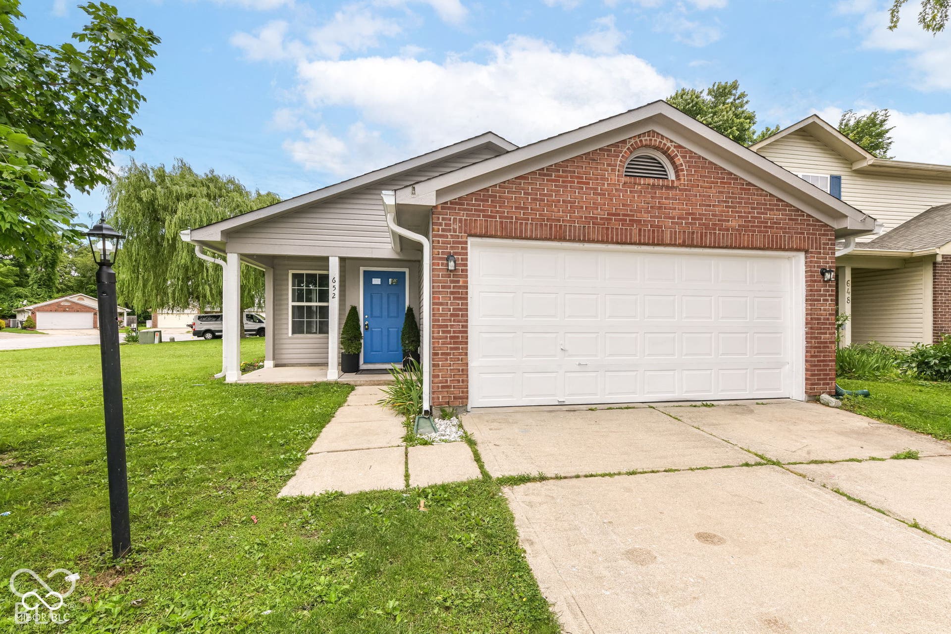 Brick and siding facade, covered entry, attached garage, concrete driveway, and front lawn