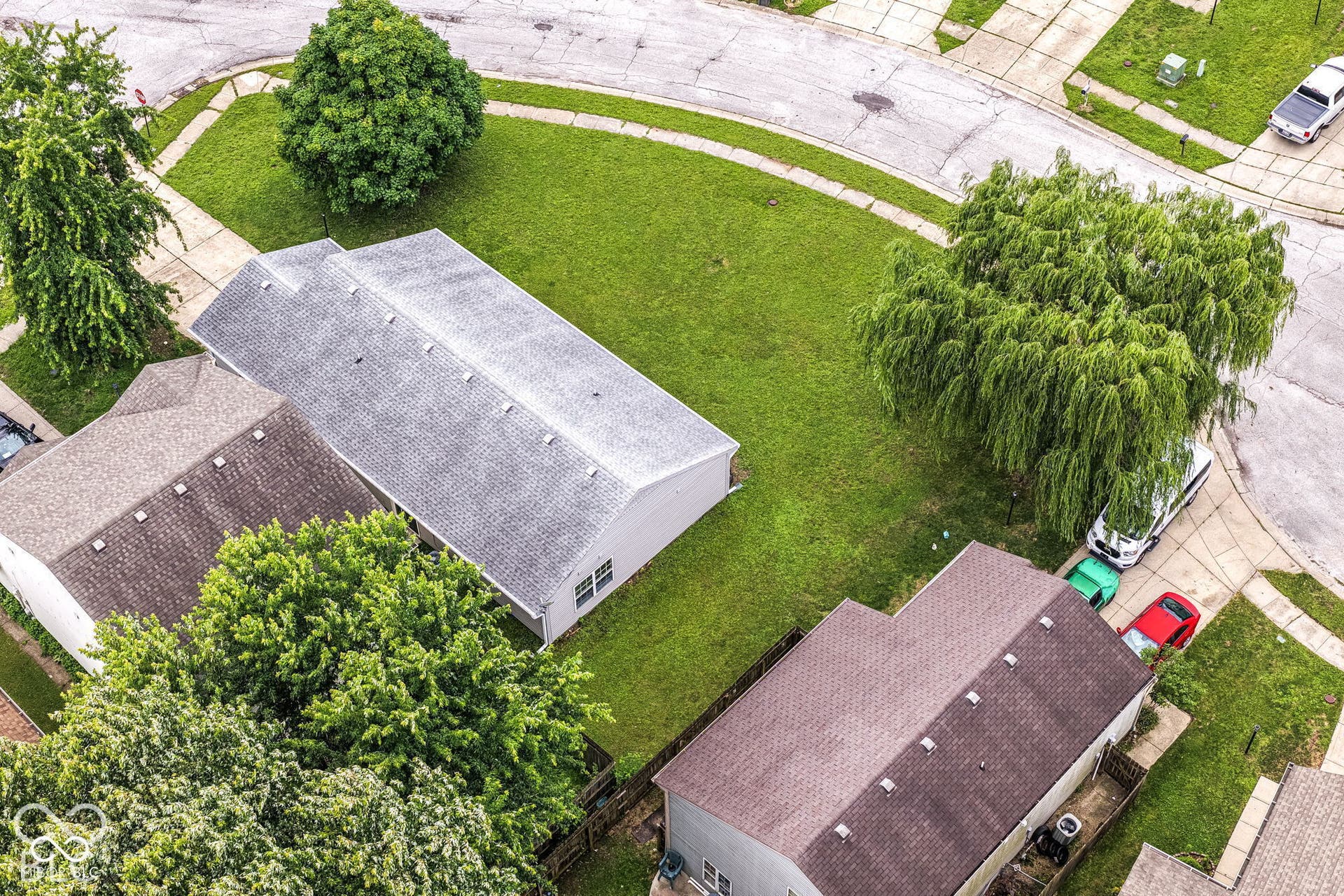 Expansive green lawn surrounds the property, featuring a mature weeping willow and additional established trees