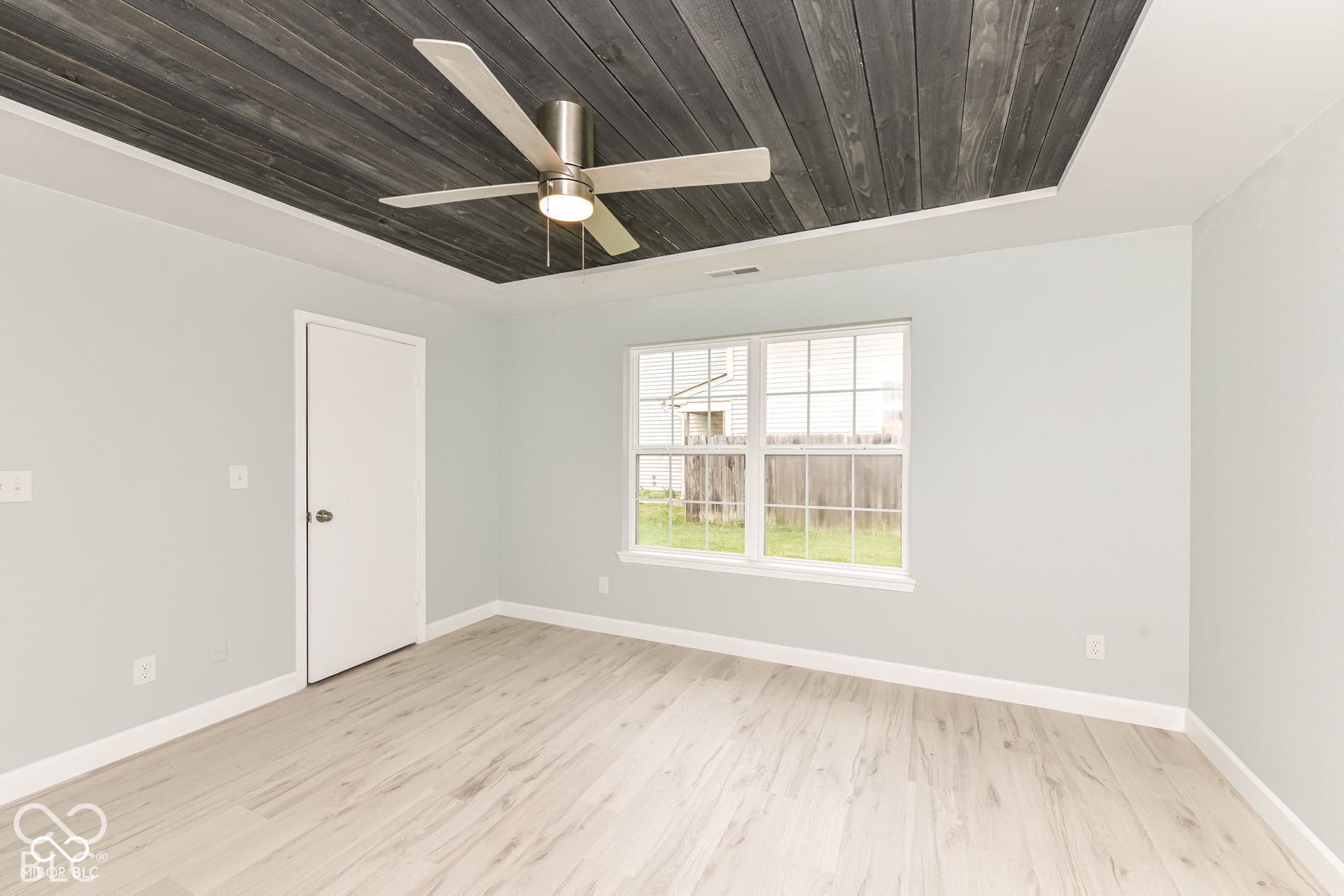 Tray ceiling with wood-plank finish, ceiling fan, wood-finish flooring, and white trim