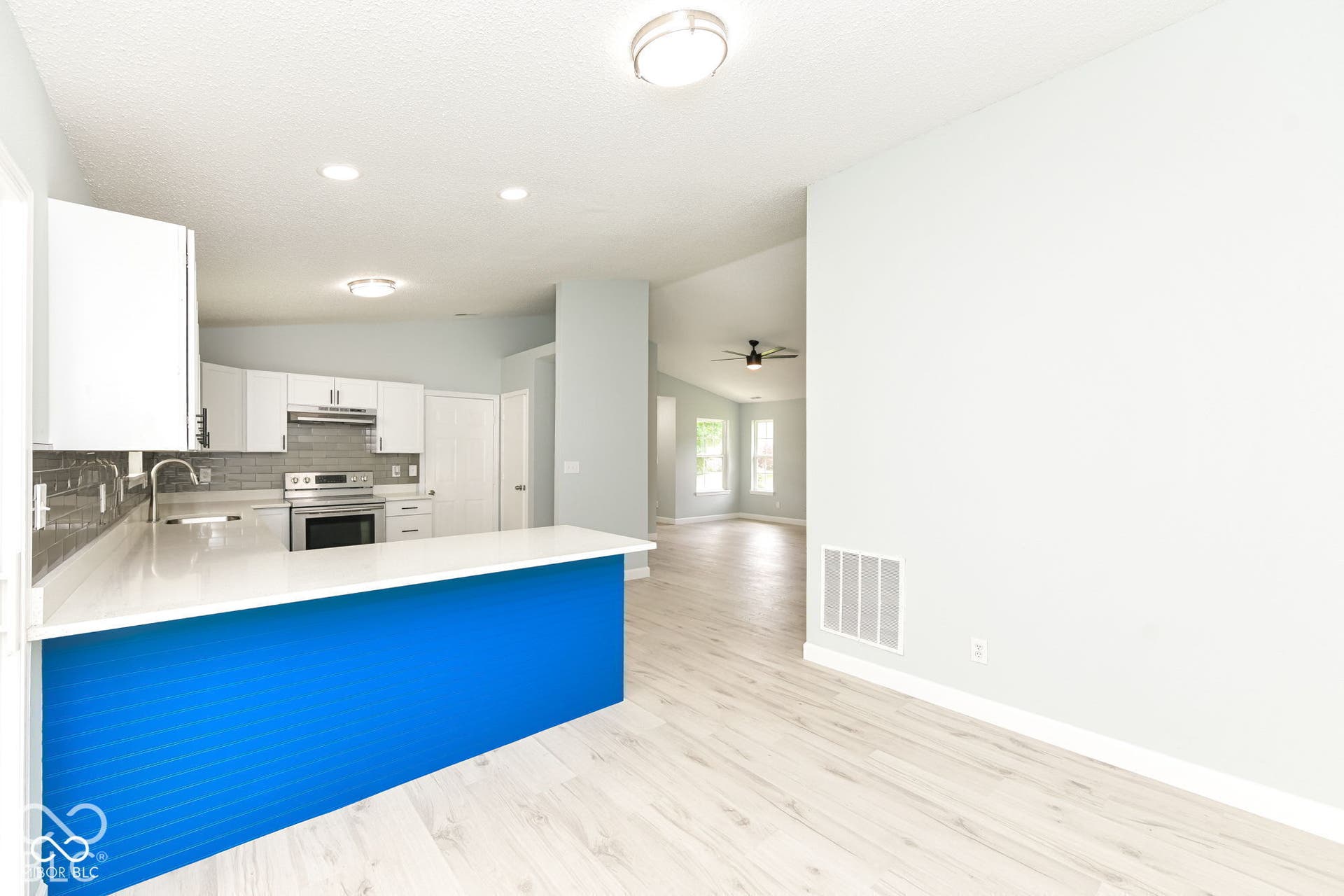 Kitchen featuring white cabinetry, stainless steel appliances, a white countertop island, and wood-finish flooring