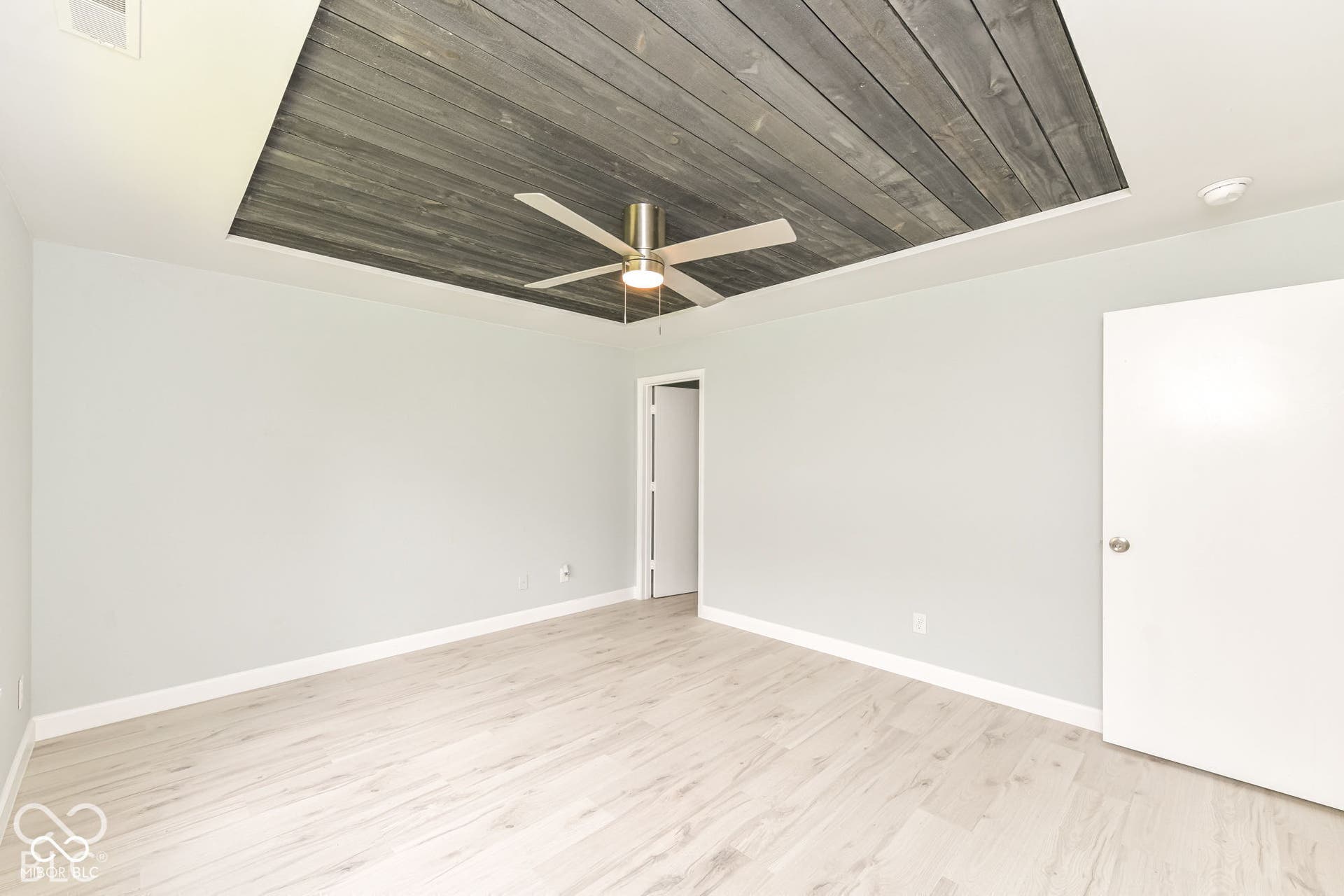 Recessed ceiling detail with wood-finish paneling, overhead ceiling fan with lighting, wood-finish flooring, and light-toned wall paint