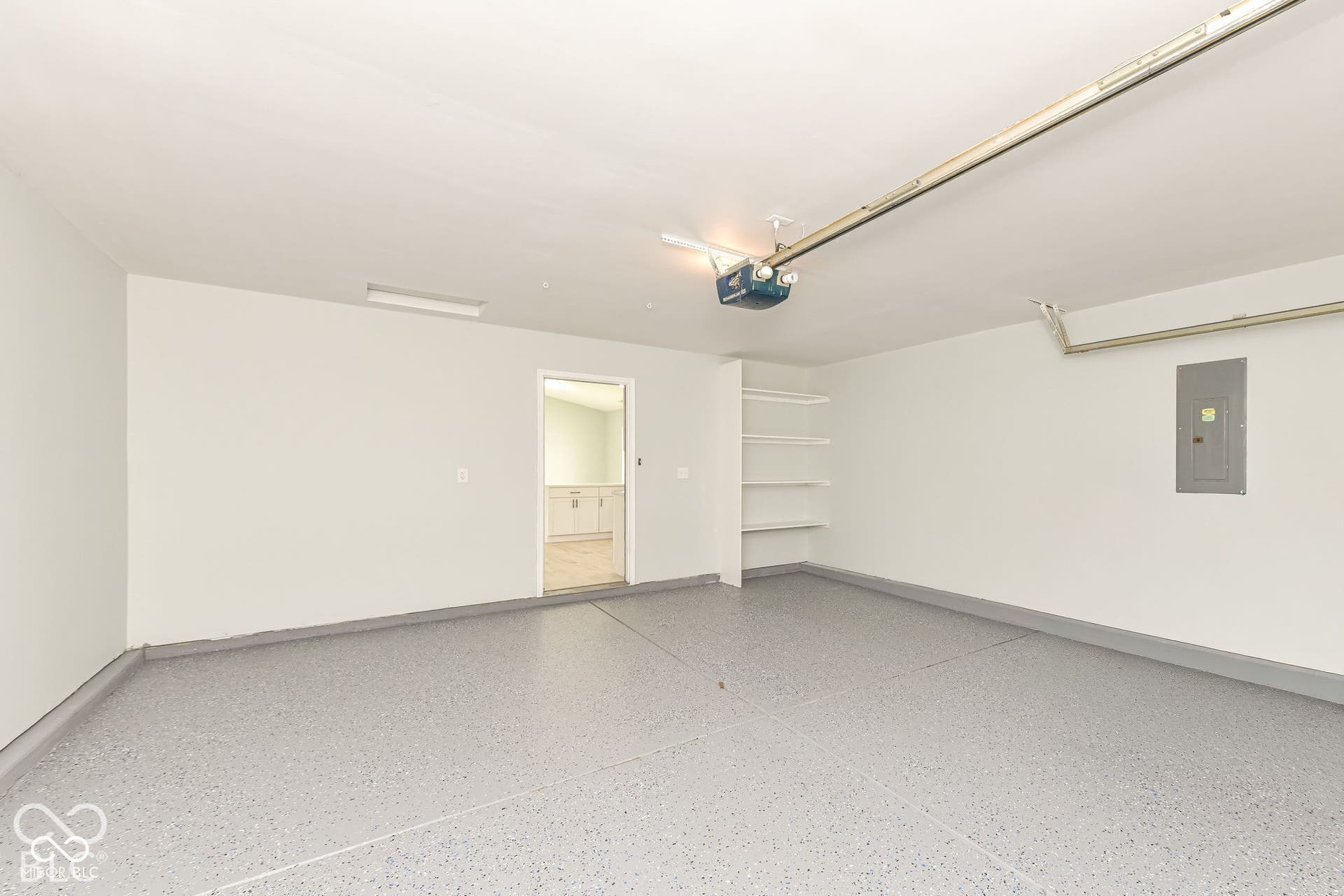 Garage featuring a speckled epoxy floor, built-in shelving, and automatic garage door opener