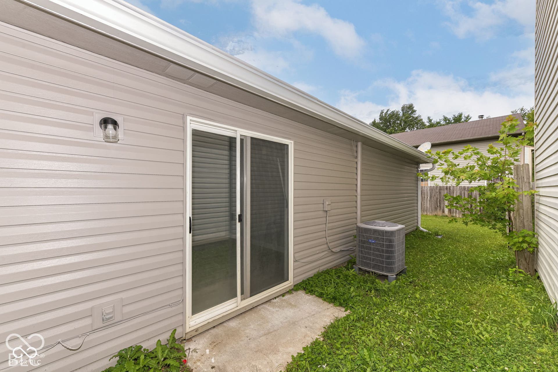Siding exterior featuring a sliding glass door, an outdoor light fixture, and an air conditioning unit