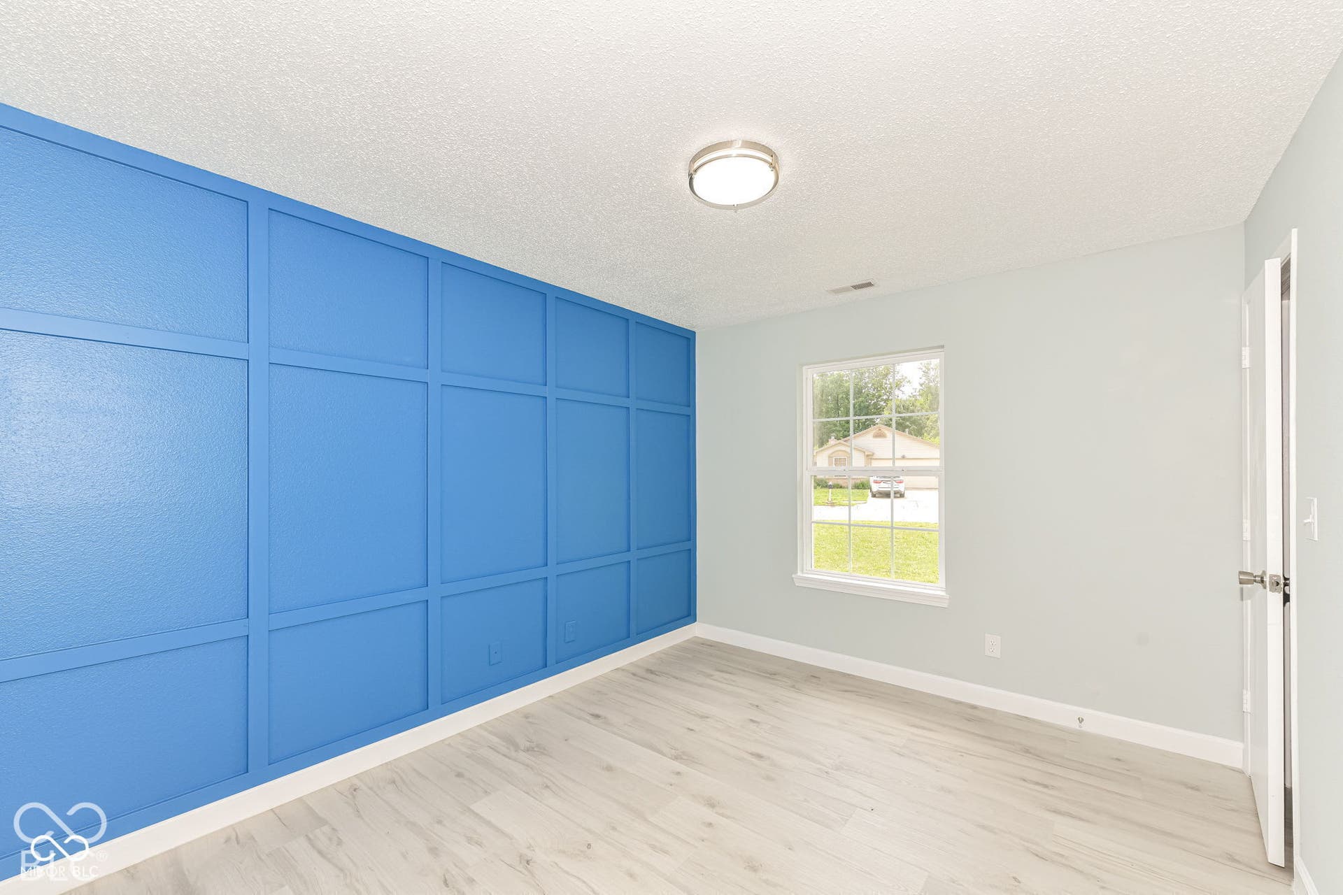 Accent wall with wainscoting, wood-finish flooring, and flush mount ceiling lighting
