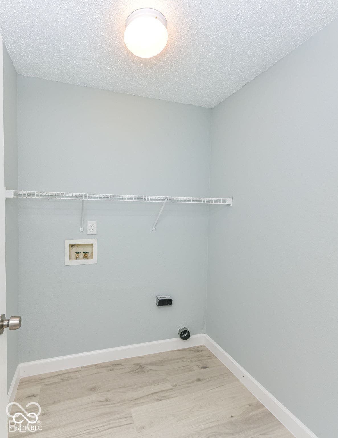 Dedicated utility area featuring wood-finish flooring and a ceiling-mounted light fixture
