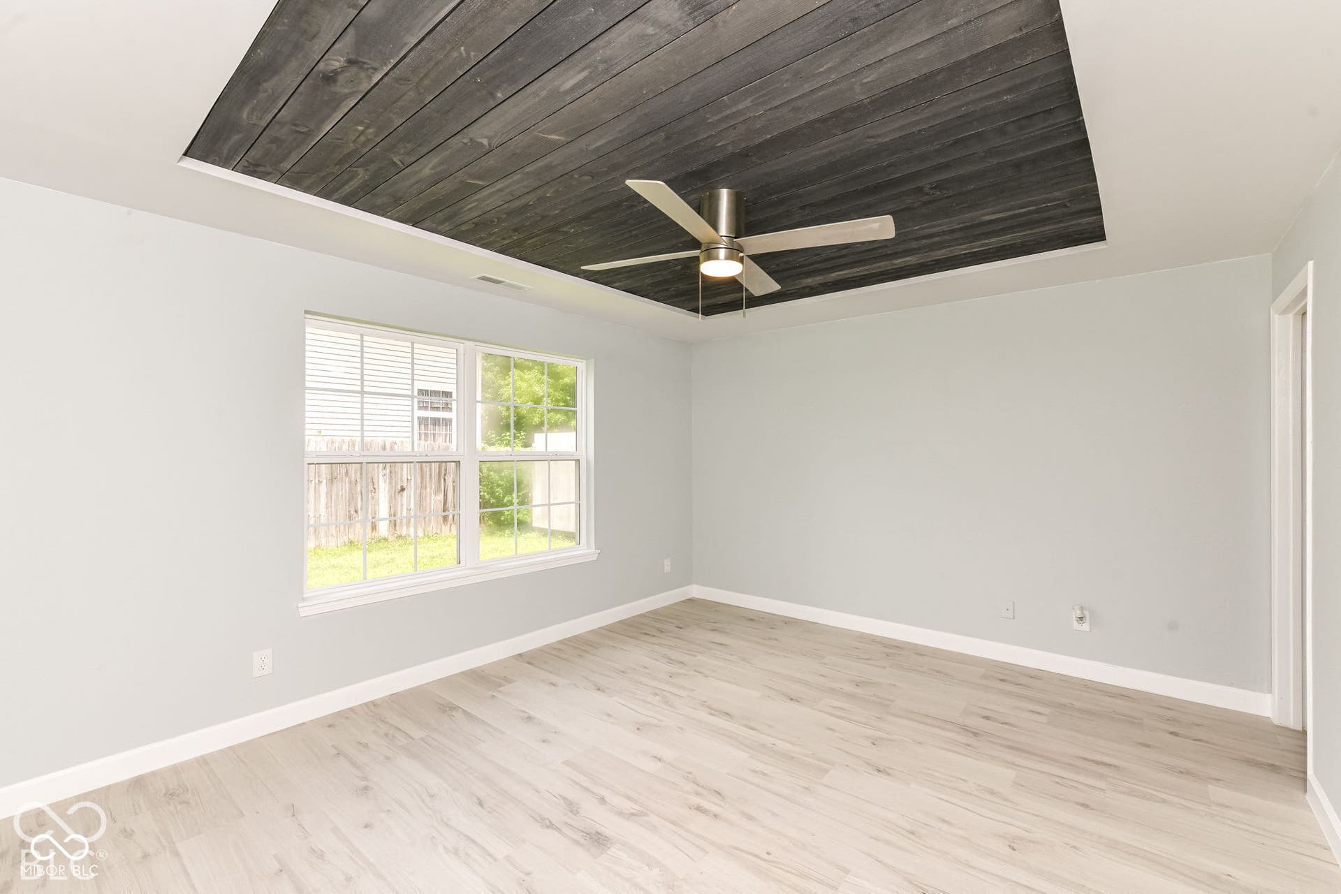 Recessed ceiling feature with dark wood-finish paneling and a ceiling fan