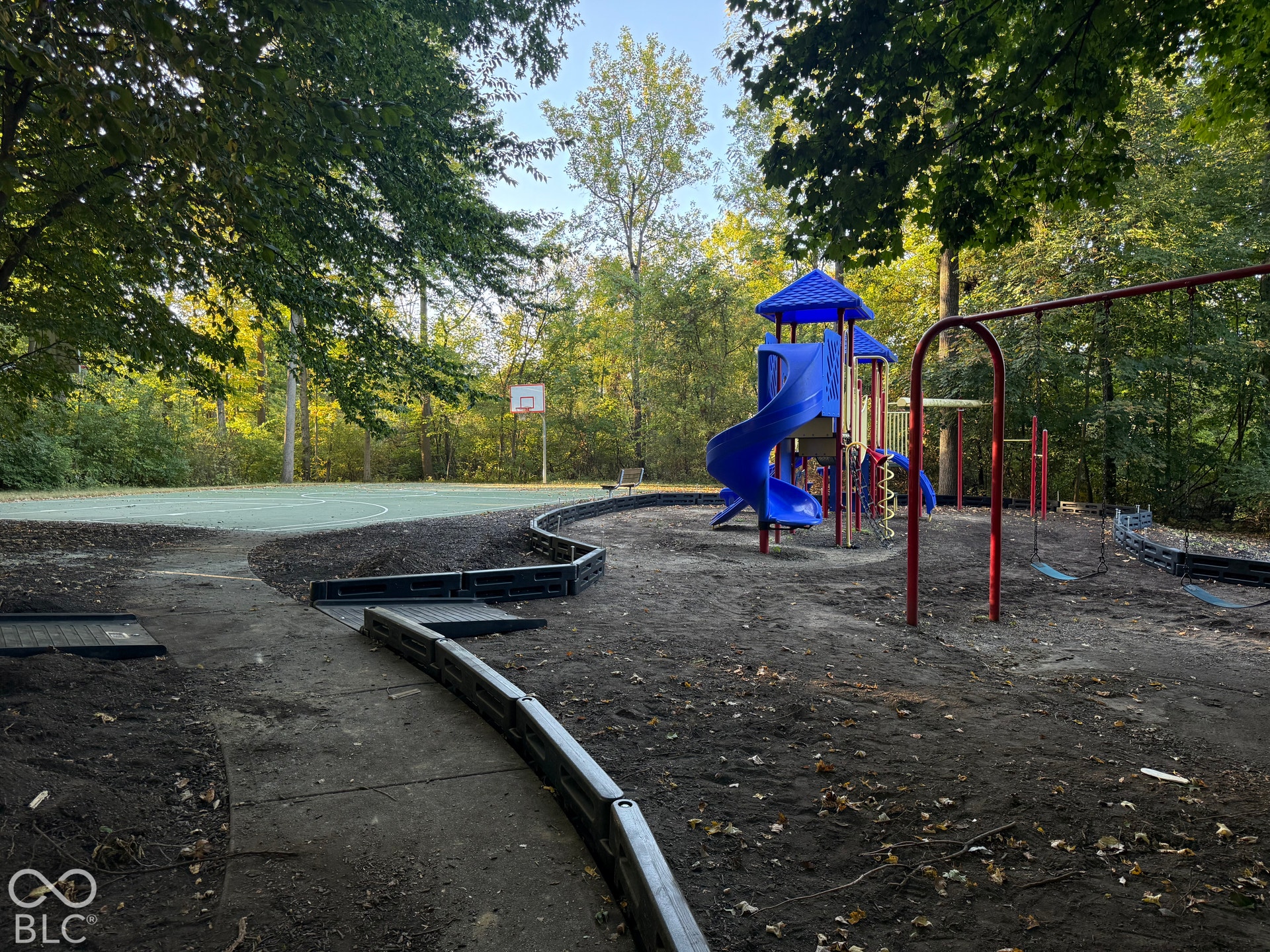 6416 Manchester Drive, Fishers, IN 46038 Neighborhood Recreational area featuring a basketball court, playground structure with slide, and swing set, surrounded by mature trees