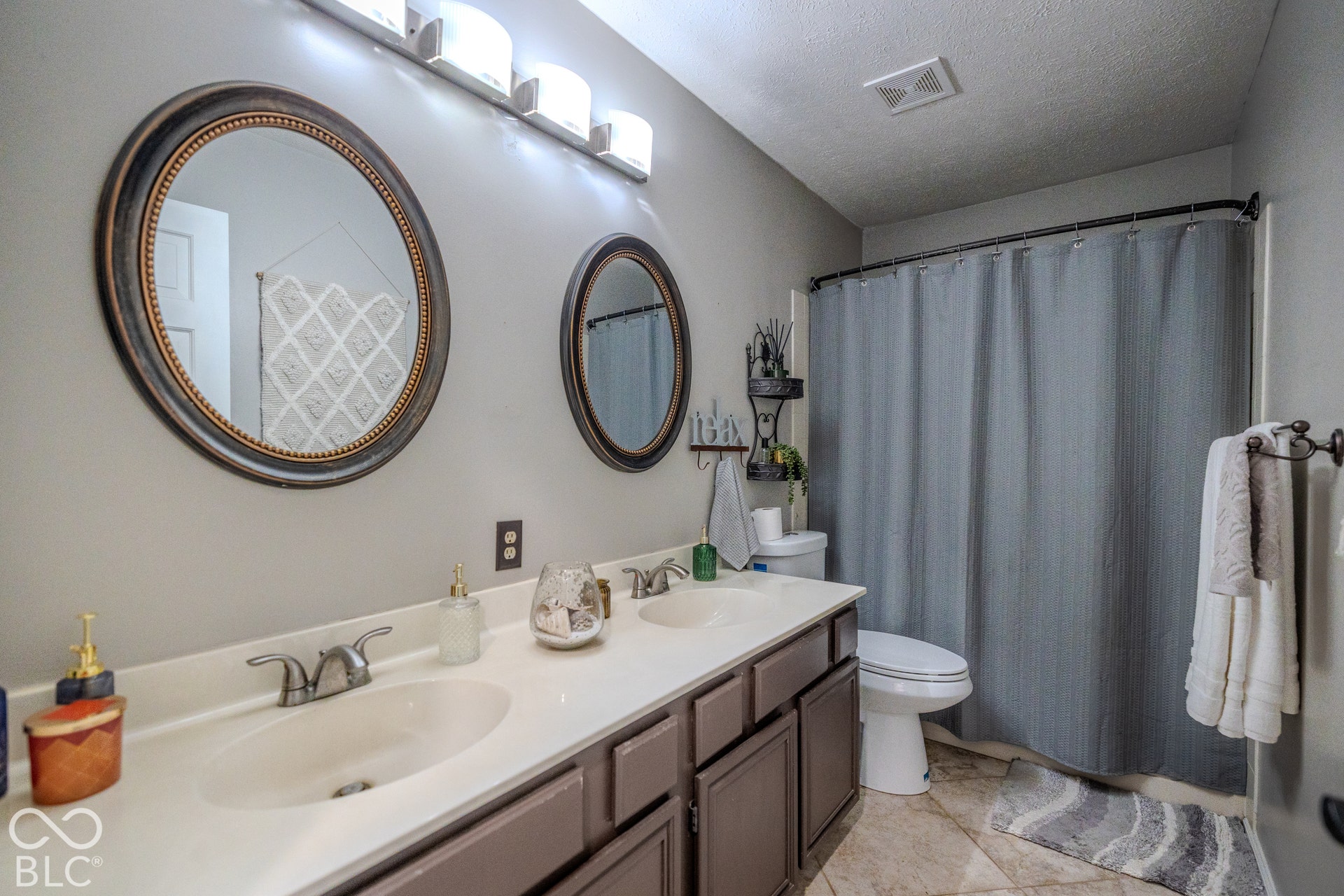 6416 Manchester Drive, Fishers, IN 46038 Main bath features Dual vanity with integrated sinks, framed oval mirrors, and overhead light fixtures. There is also a combination tub and shower.