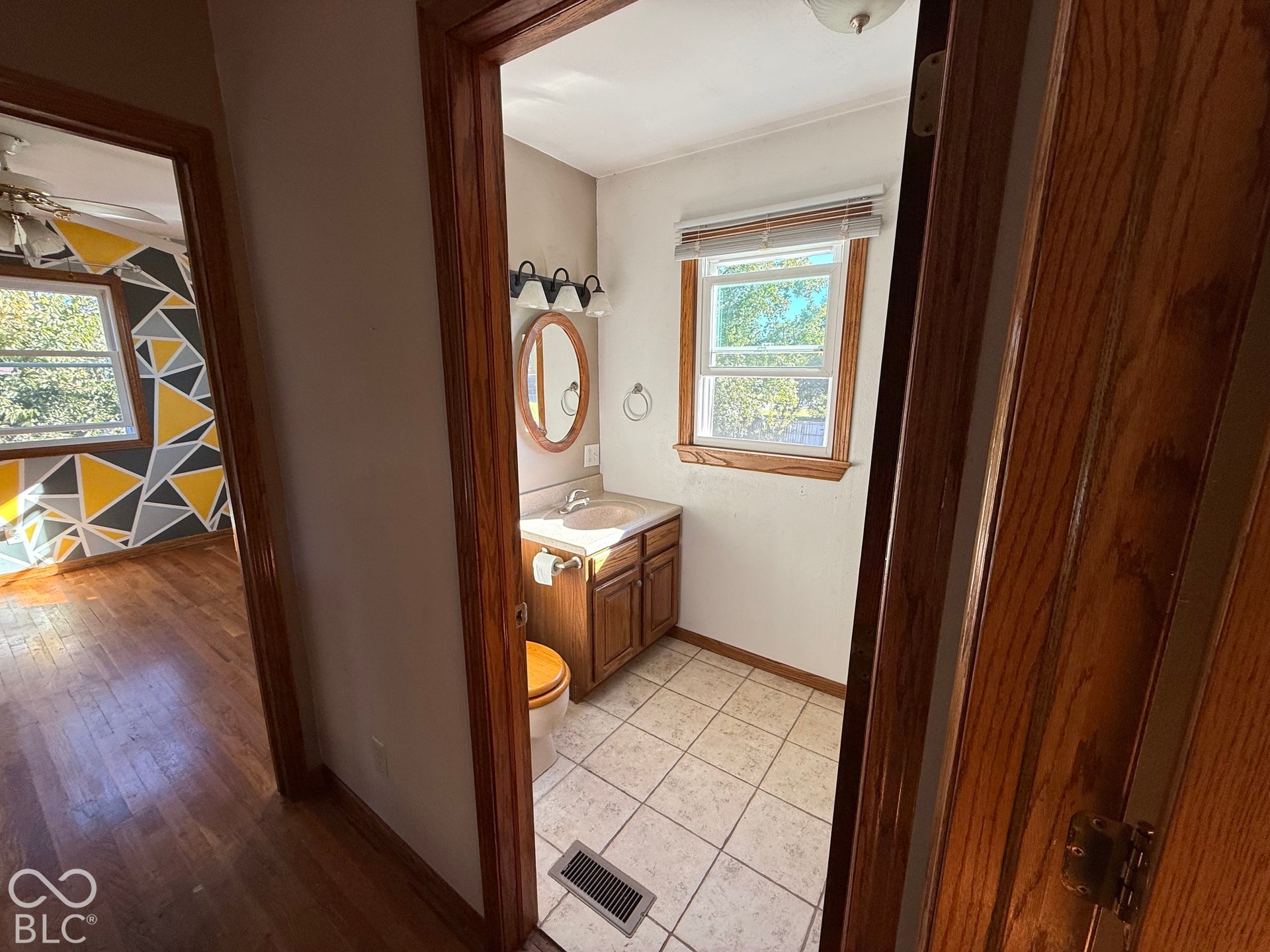 Bathroom with a wood-finish vanity, integrated sink, and wall-mounted light fixture