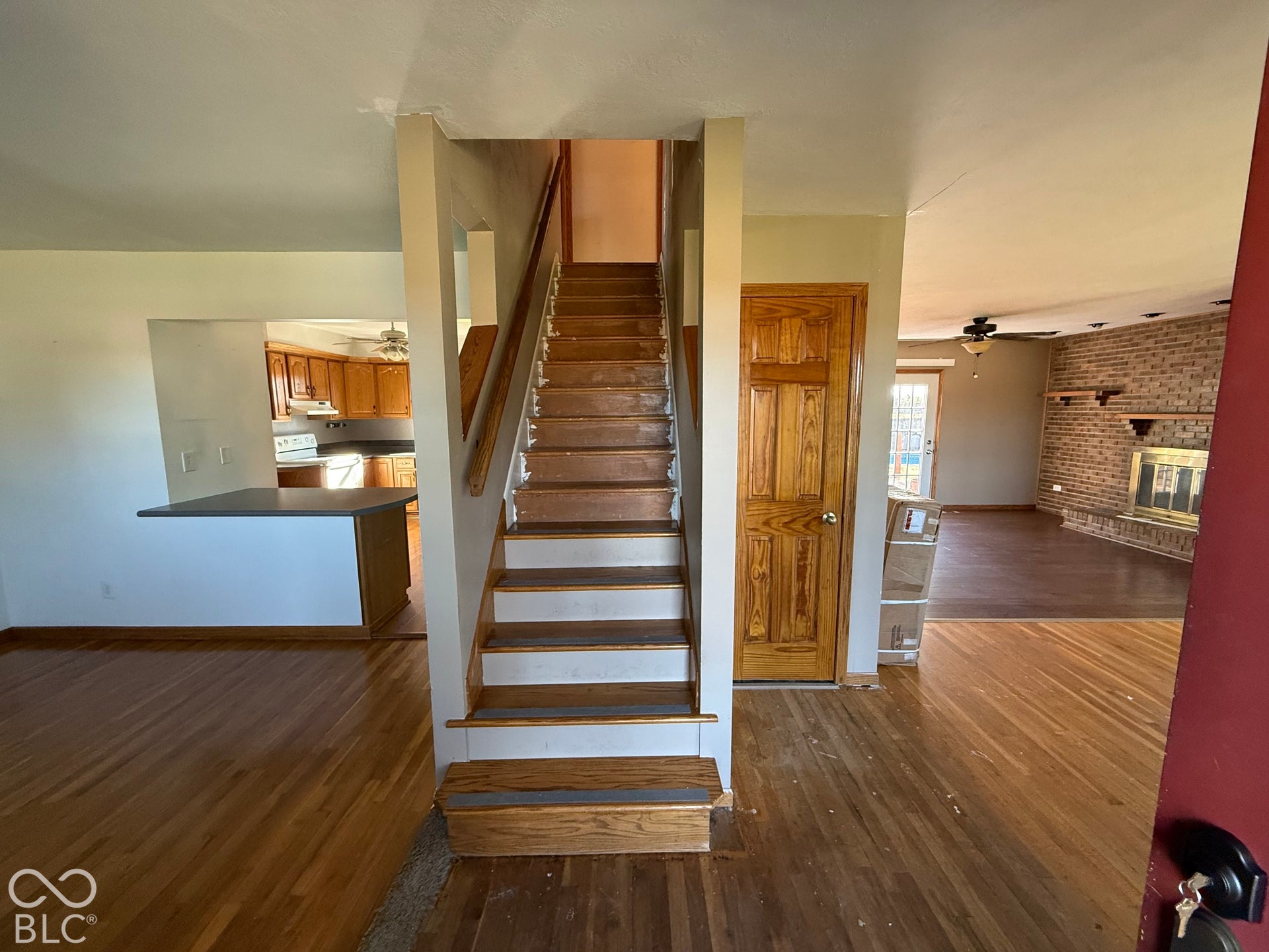 Hardwood flooring throughout, a staircase with wood treads, and a built-in kitchen bar