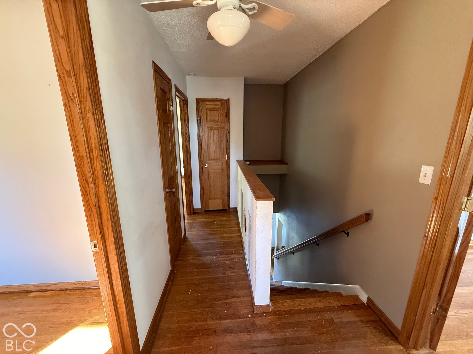 Wood-finish flooring throughout, solid wood doors, and a staircase featuring a wood-finish handrail and balusters
