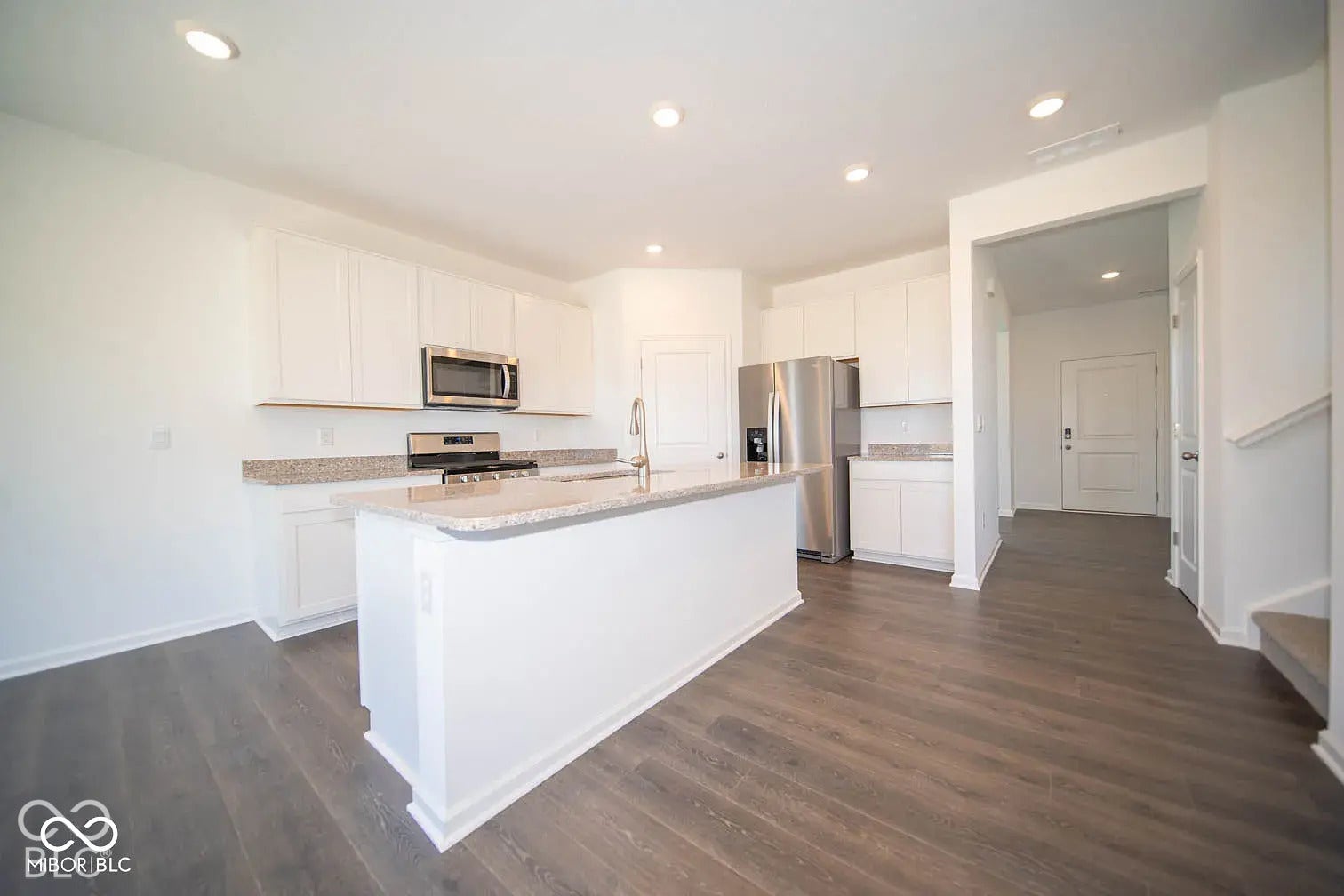 5778 Aleppo Lane, Greenwood, IN 46143 Open-concept kitchen with white cabinetry, stainless steel appliances, granite countertops, and a central island with a sink