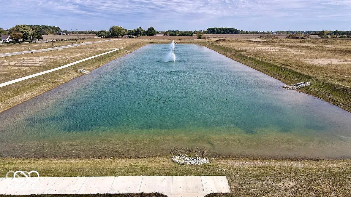 5778 Aleppo Lane, Greenwood, IN 46143 Expansive water feature with a central fountain, bordered by a walking path and open green space