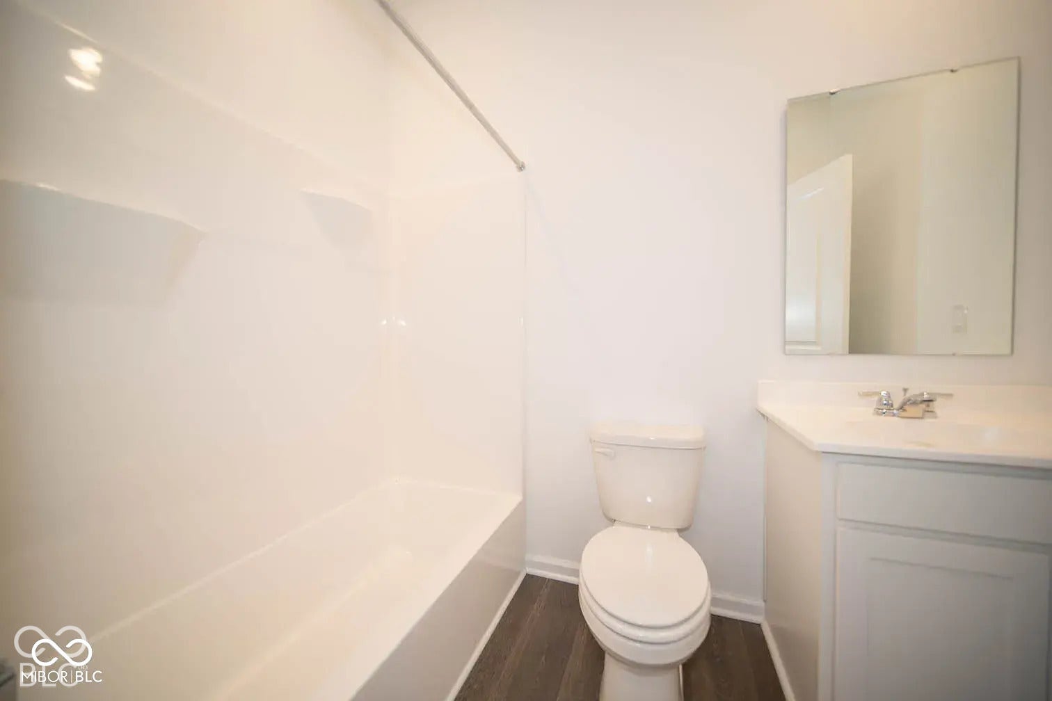 5778 Aleppo Lane, Greenwood, IN 46143 Bathroom featuring a white bathtub and shower surround, a white toilet, a white vanity with a single basin sink, and wood-finish flooring