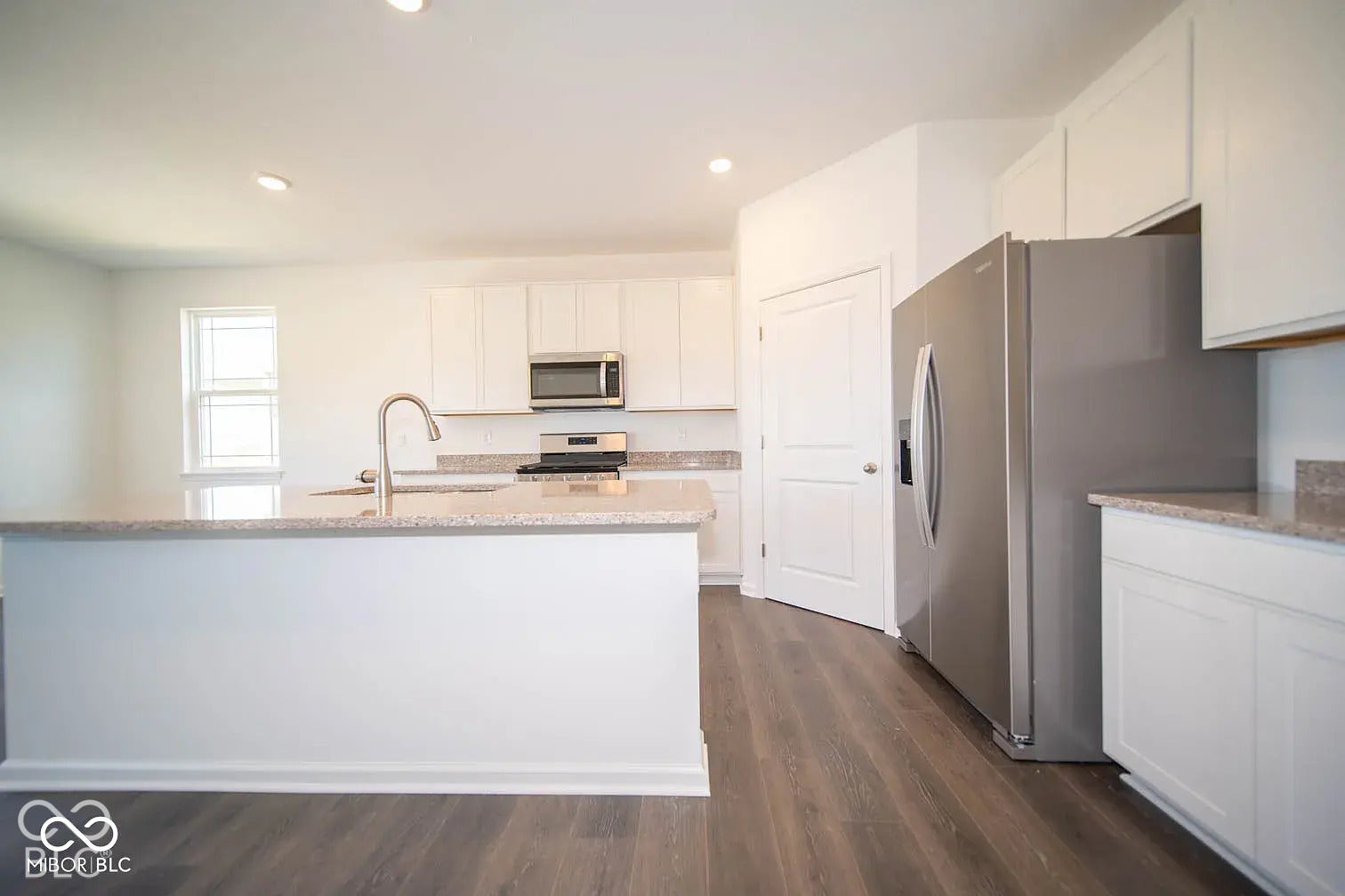 5778 Aleppo Lane, Greenwood, IN 46143 Kitchen featuring a central island, stainless steel appliances, white cabinetry, and wood-finish flooring