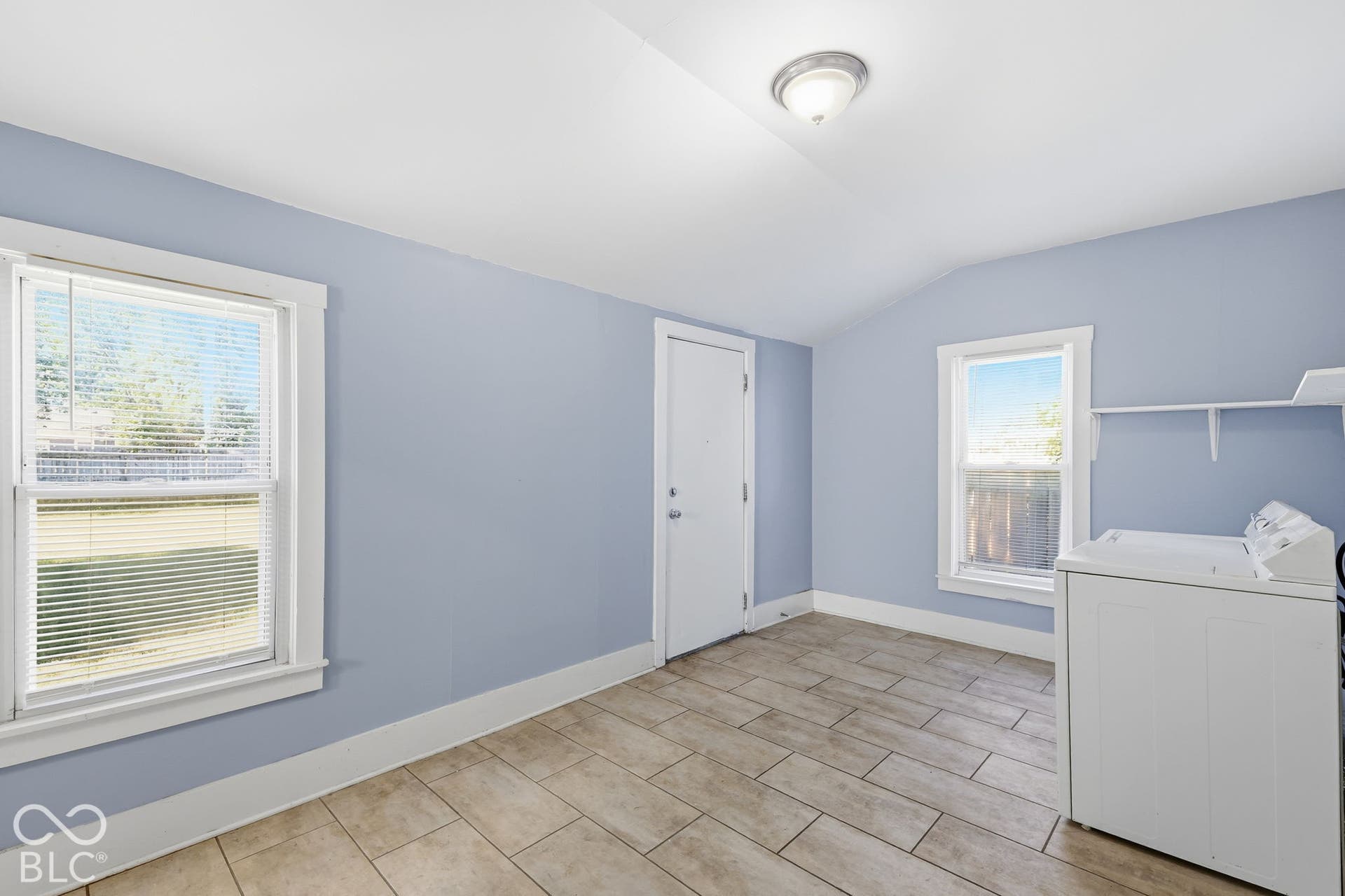 Tile flooring, white window trim, built-in shelving, two windows, and a flush mount ceiling light