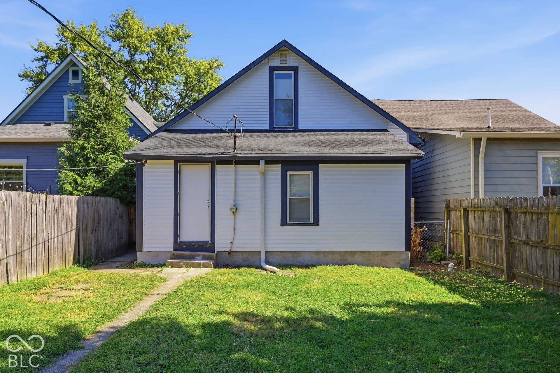 Siding exterior with contrasting trim, a gabled roofline, and a ground-level entry door
