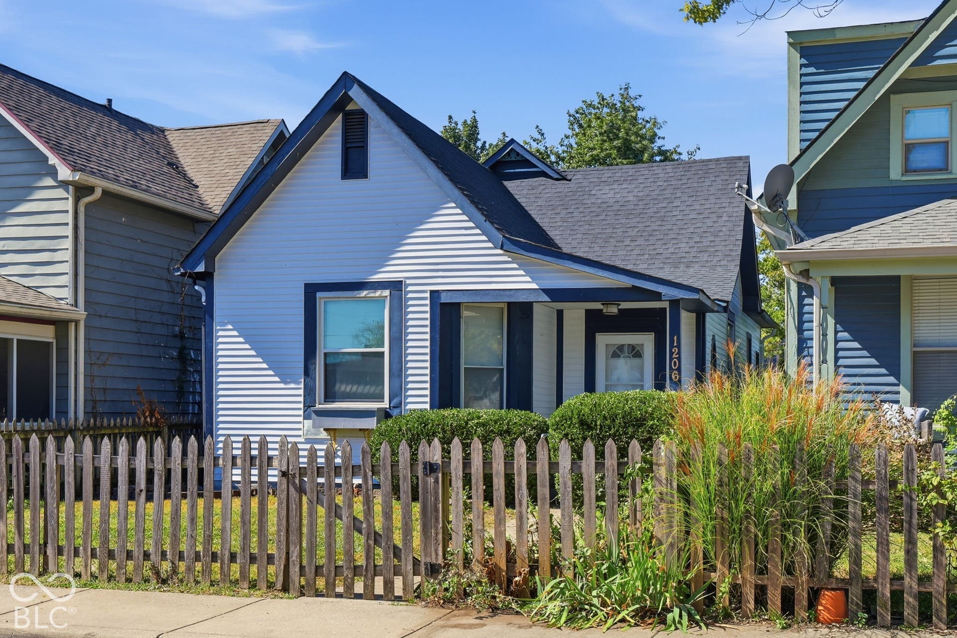 White siding exterior with dark trim accents, covered front porch, and a peaked roofline