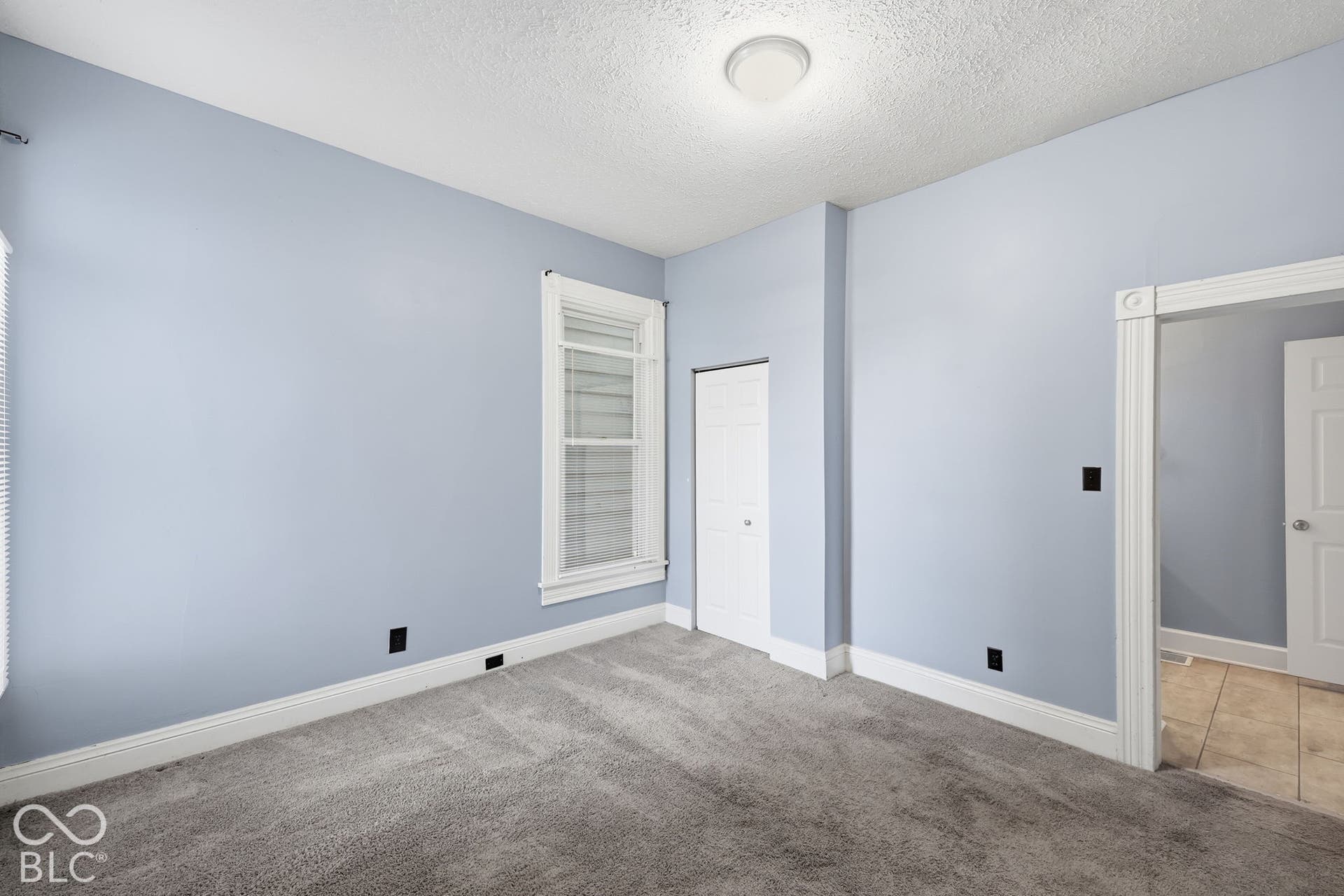 Recessed overhead lighting, gray carpet flooring, white trim, and a white bi-fold closet door