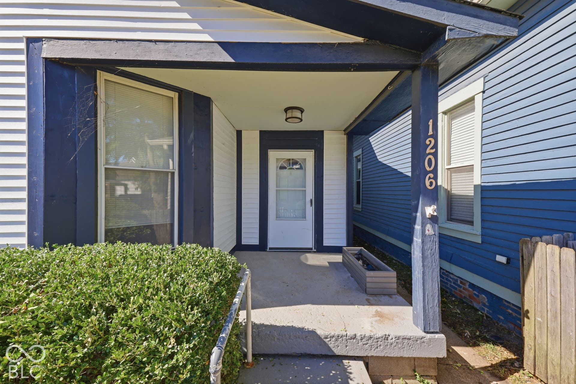 Covered front porch with concrete flooring and white vertical siding