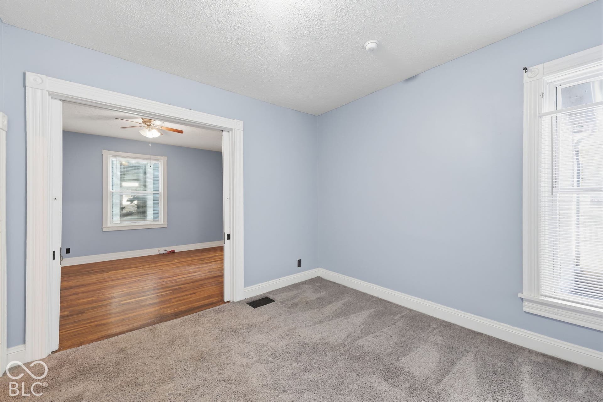 Light blue wall paint, gray carpeting, white trim, and a white window with blinds