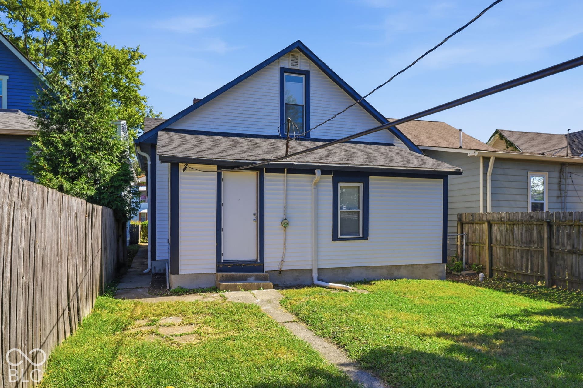 Vinyl siding exterior with a dark trim, featuring a gable roofline and a fenced backyard with a grass lawn
